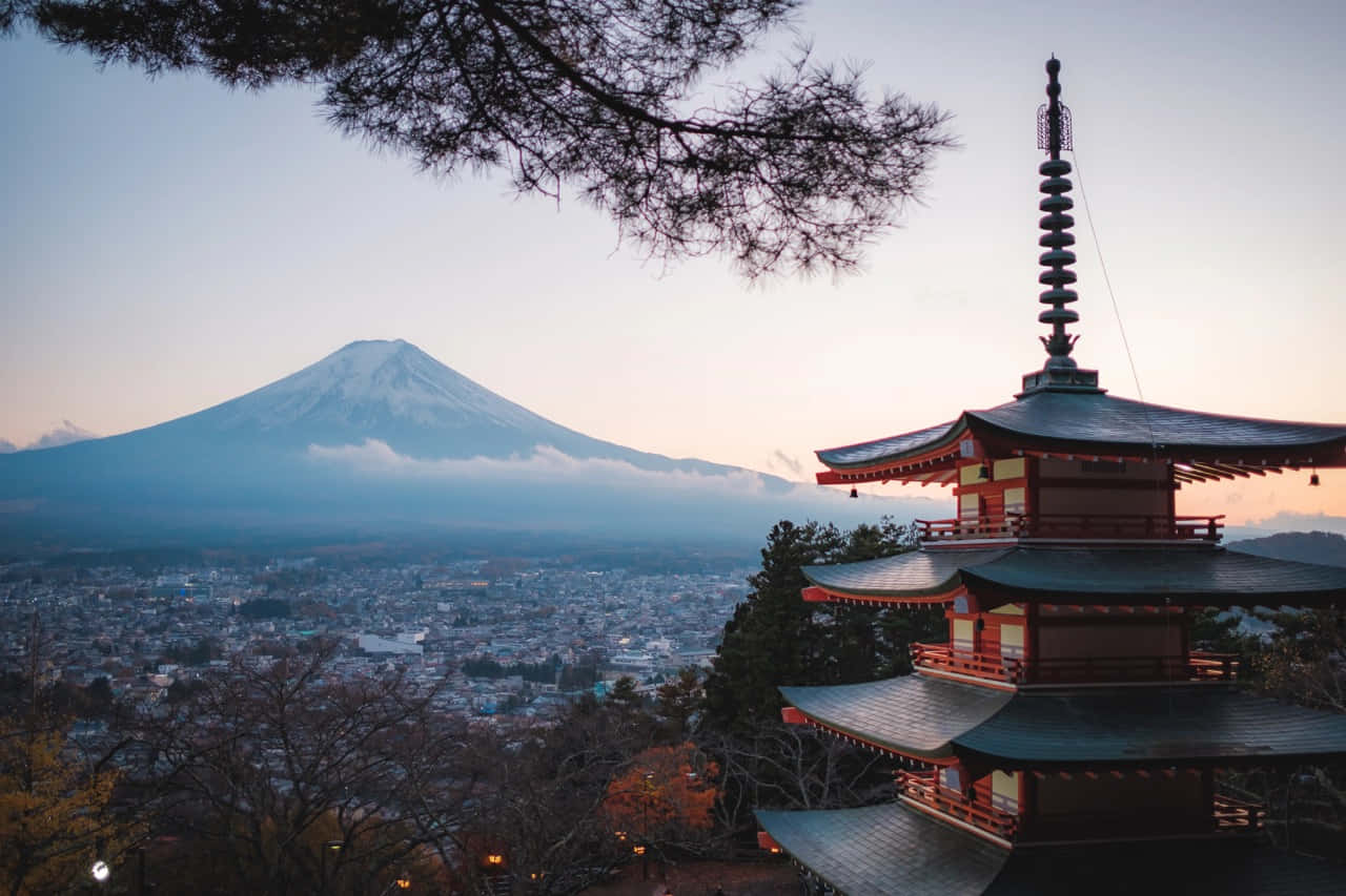 壯麗山湖風景 壁紙 — 一座傳統日本寶塔矗立在前景，富士山的雪頂山峰在黃昏時分從霧氣瀰漫的小鎮後方升起。