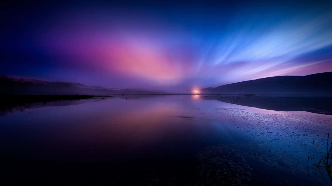 壯麗日落風景 1366x768 監視器背景 壁紙 — 寧靜的暮色湖泊映照出充滿活力的紫色和藍色天空，遠山在薄霧中漸漸消失。