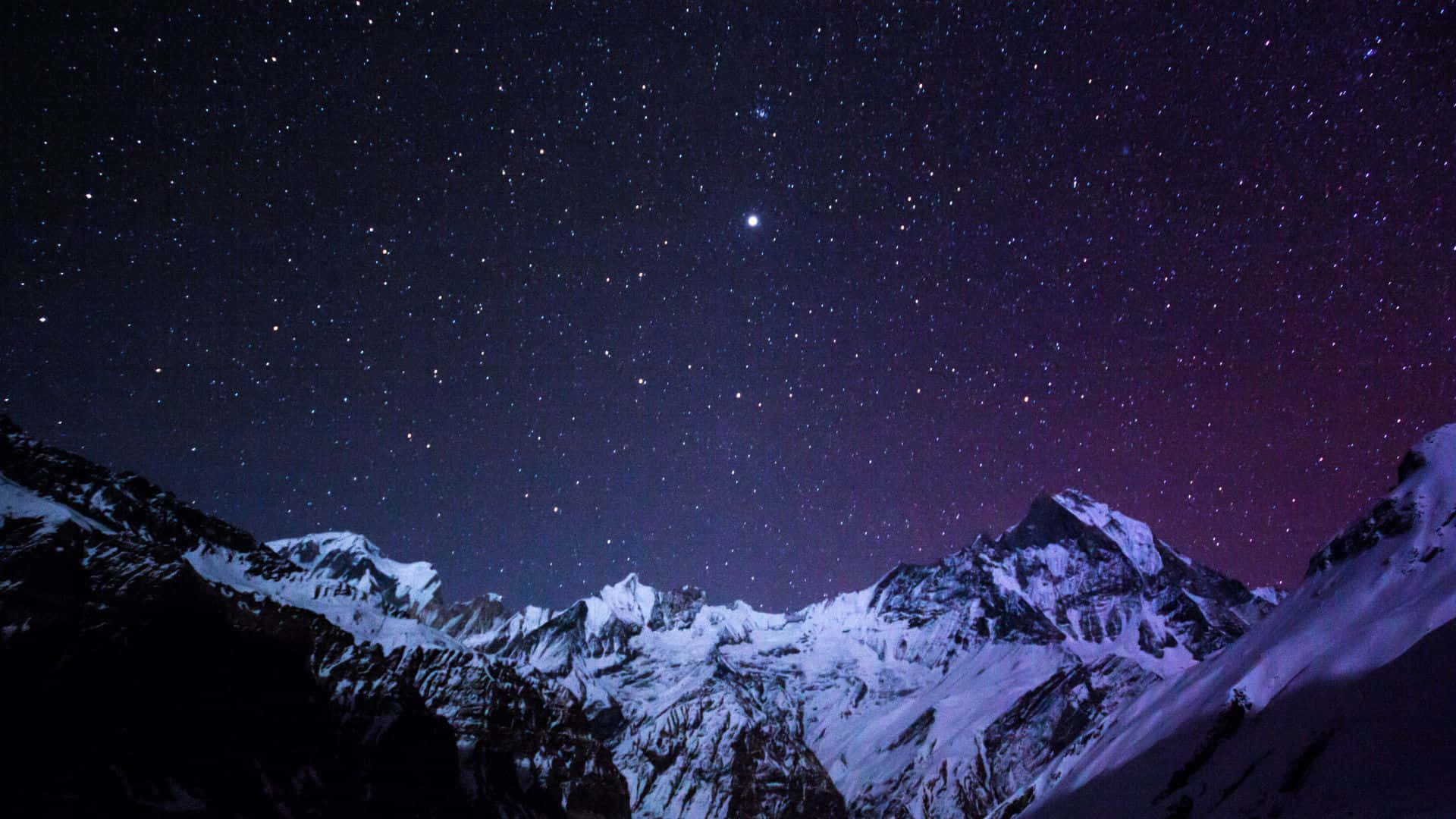 在星空紫色夜空下，積雪的山脈與極光。