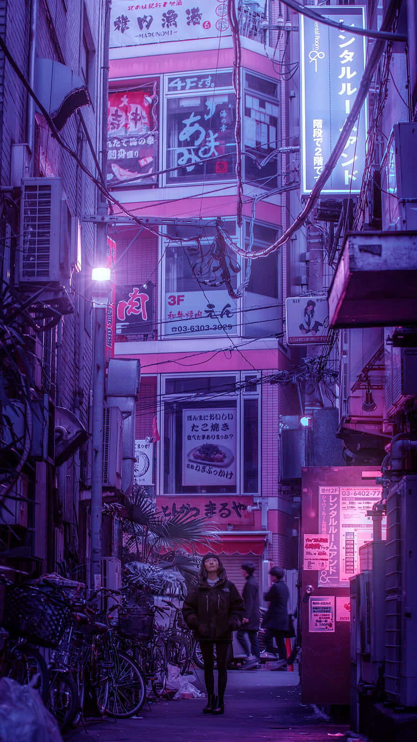 人在夜晚走過霓虹燈照亮的日本小巷