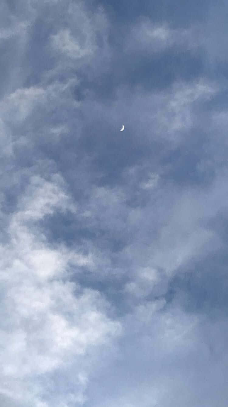 壯麗雲海全景 壁紙 — 一彎纖細的月牙在佈滿縷縷藍白雲朵的廣闊天空中柔和地發光。