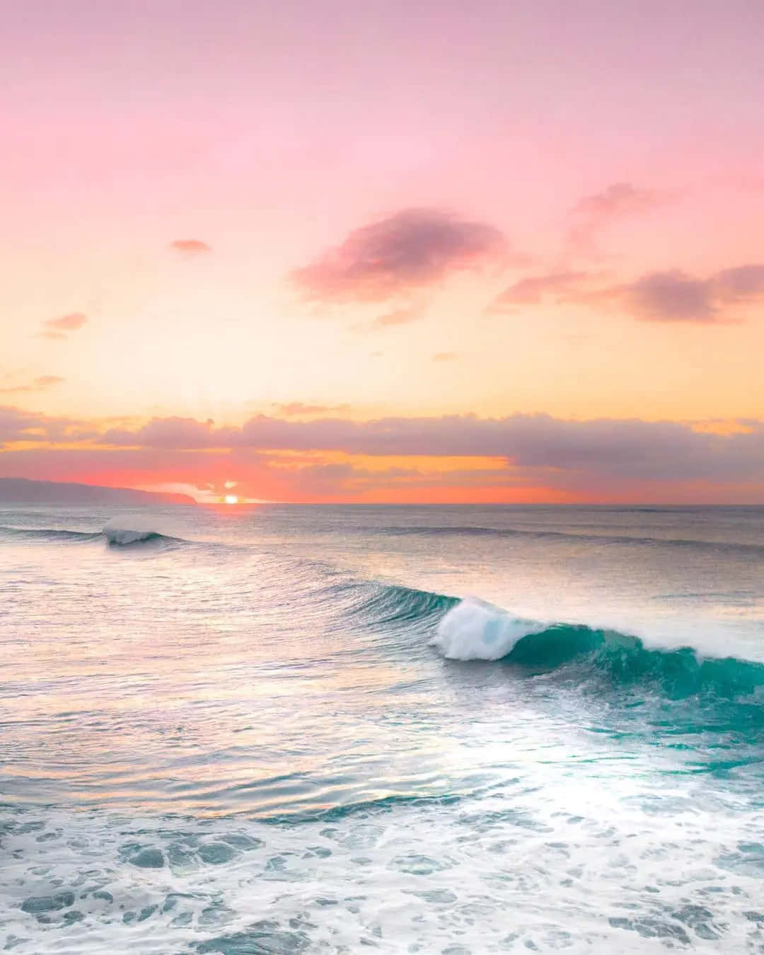 夏威夷夕陽與海浪風景 壁紙 — 寧靜的海洋日落，粉橙色天空，青綠色的海浪拍打岸邊。