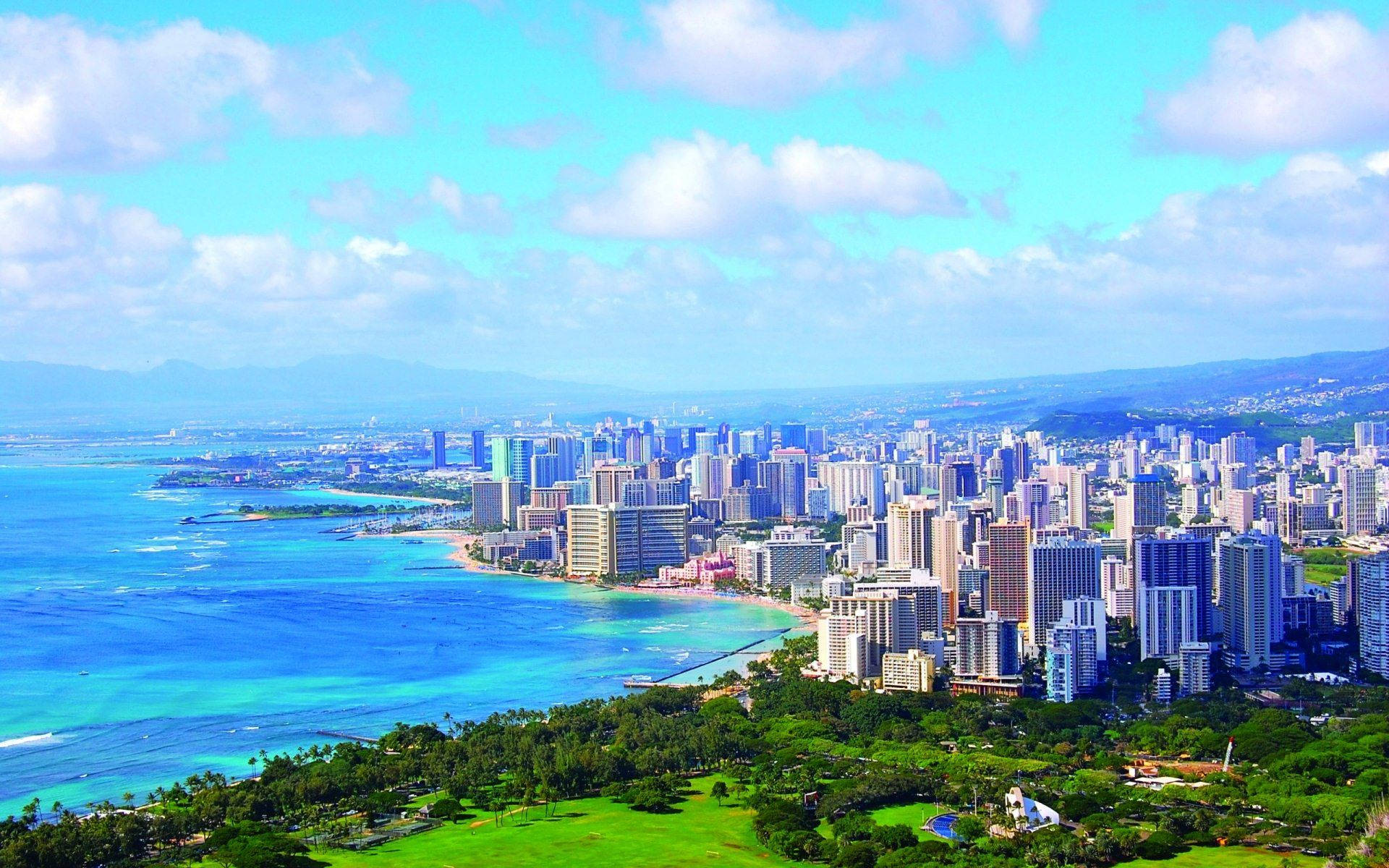 沿海城市天際線，在陽光明媚的天空下，碧綠的海水和綠色山丘。