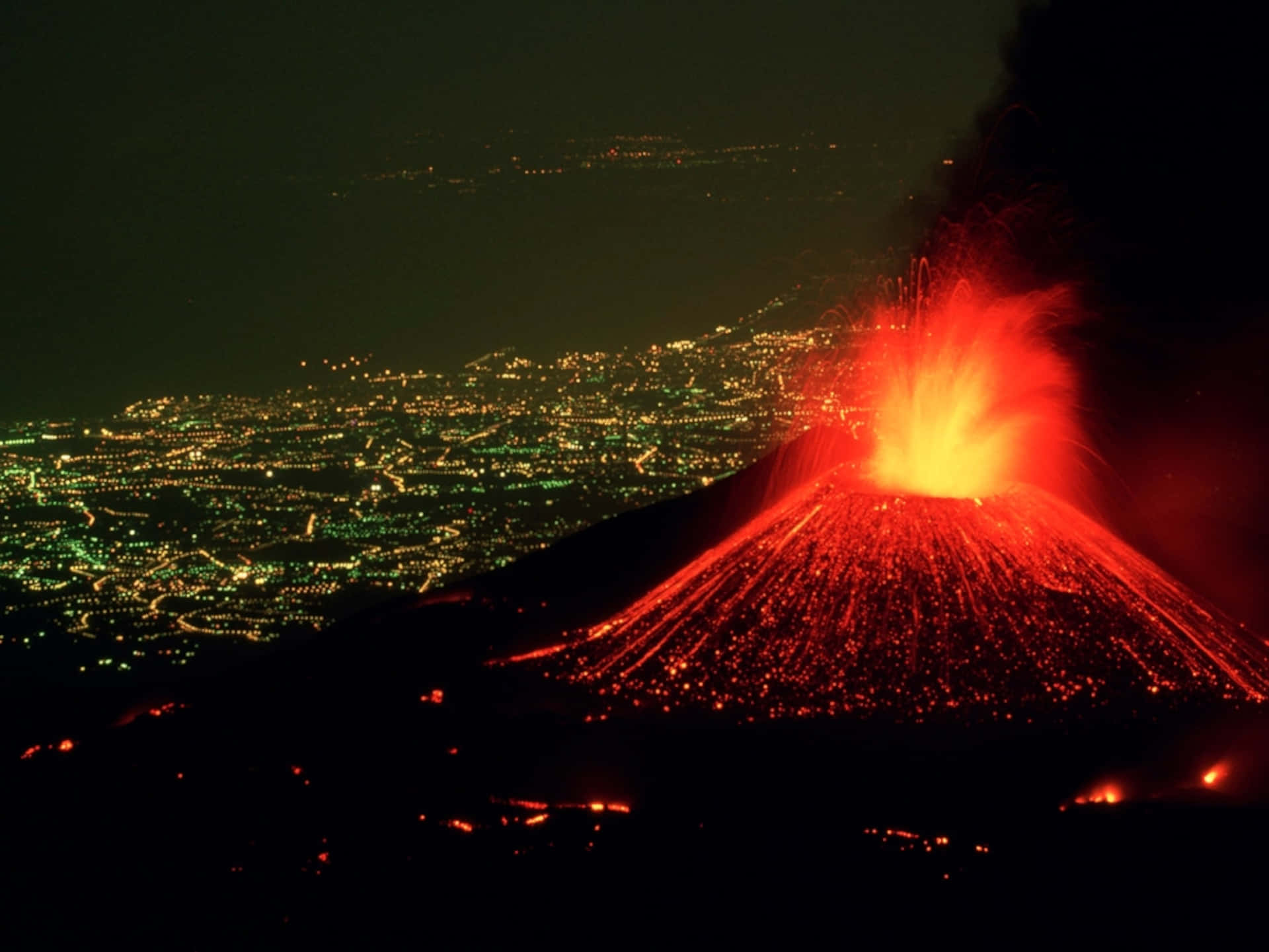 夜間火山爆發，熔岩發光，下方城市燈光