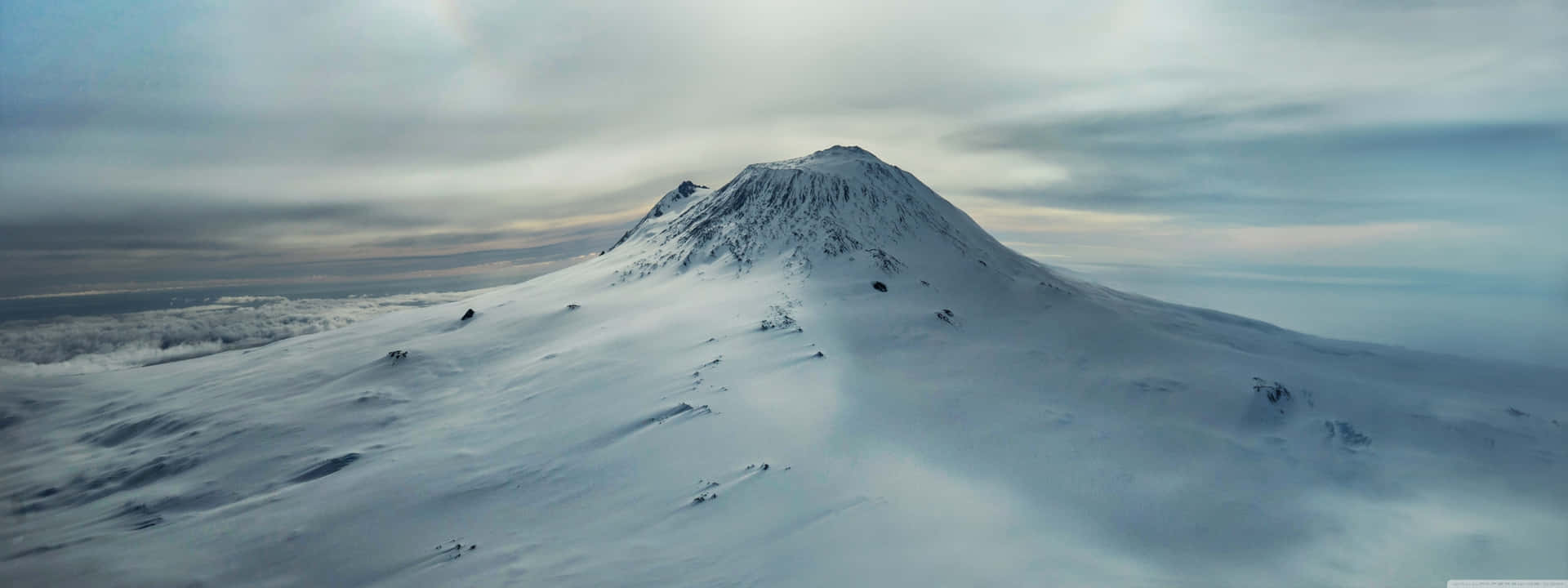 白雪覆蓋的山峰在雲層之上，天空灰暗