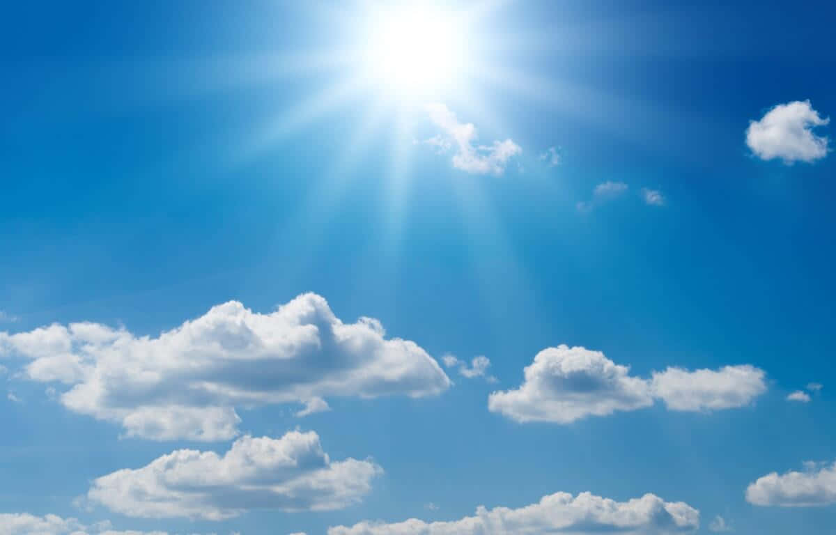 夏日晴光灑落 壁紙 — 燦爛的太陽在點綴著蓬鬆白雲的鮮豔藍天上放射出明亮的光芒。