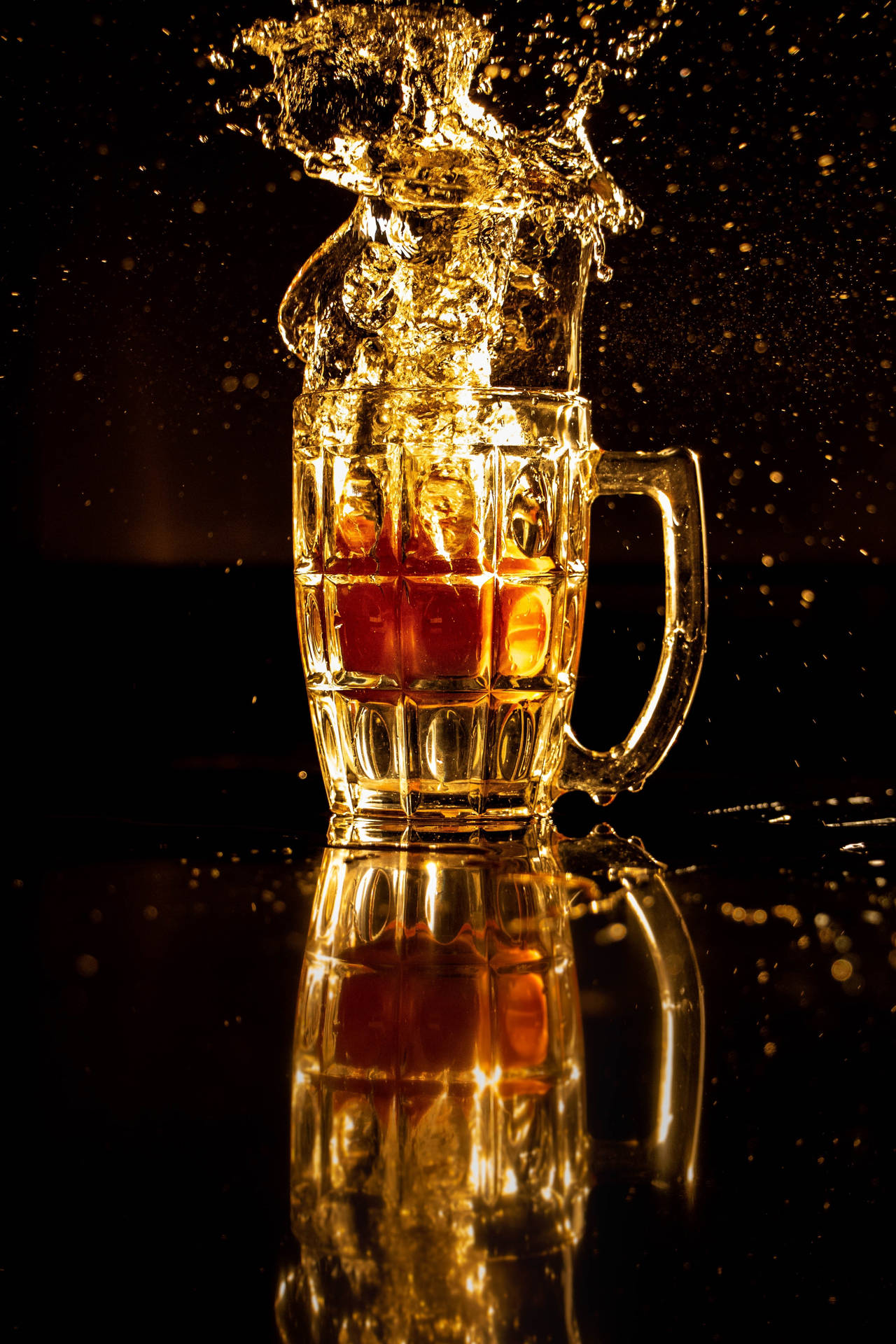 金色啤酒從玻璃杯濺出，落在深色反光表面上。