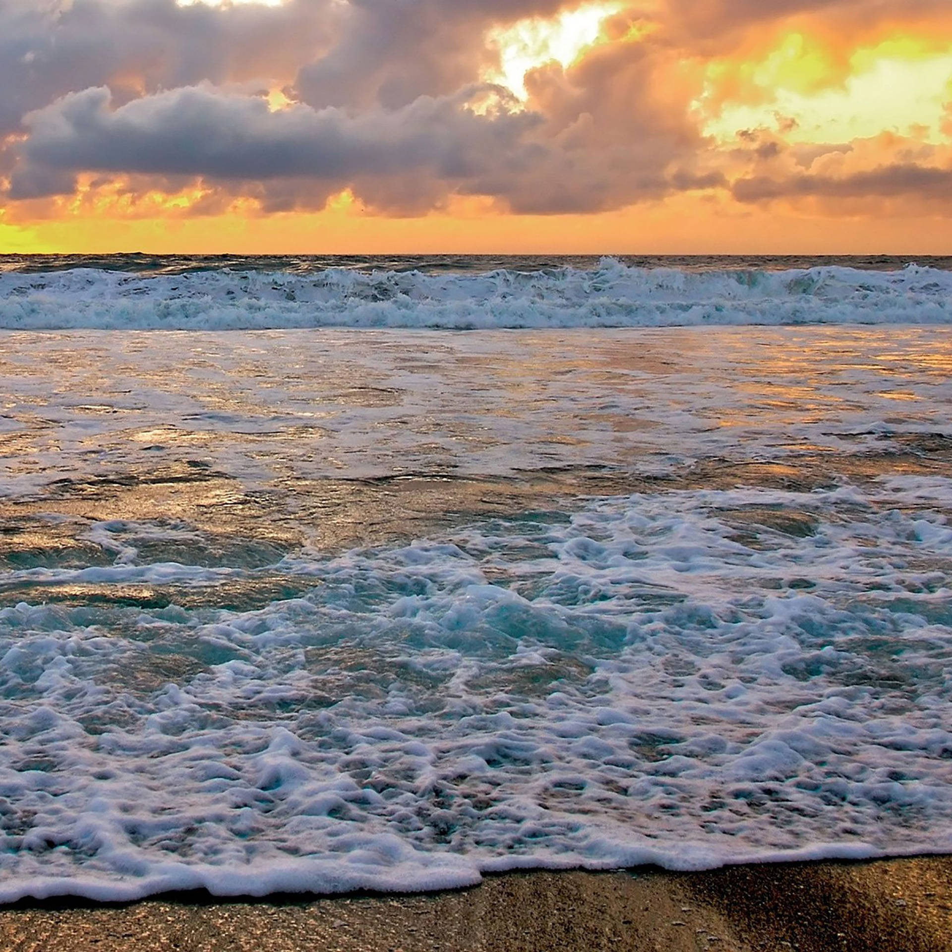 夕陽下海浪拍打沙灘，天空呈現火熱的橙色。