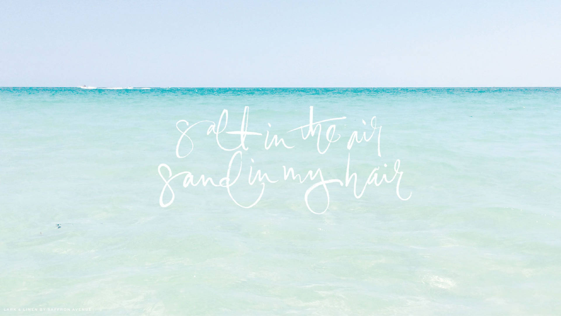 藍綠色海洋上的白色草書文字 salt in the air sand in my hair