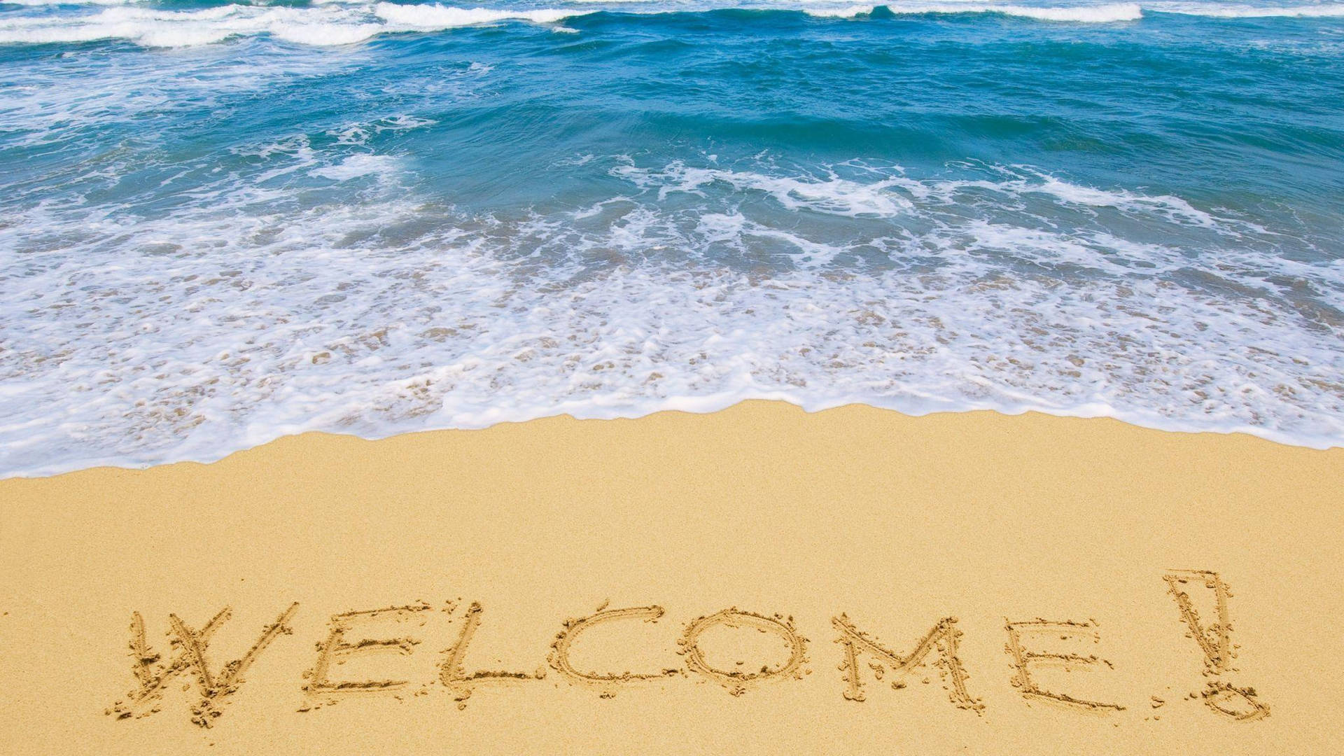 在海浪邊緣的沙灘上寫著WELCOME