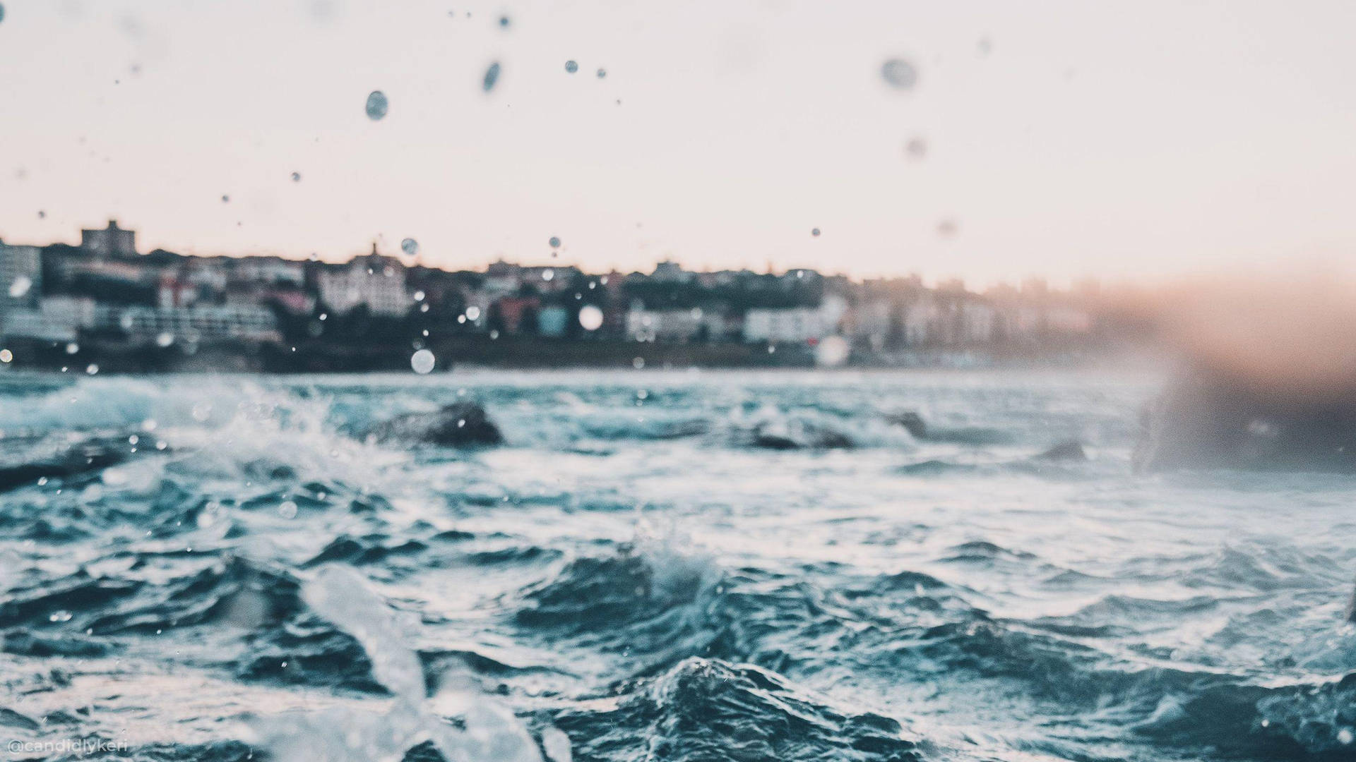 海浪在暮色中帶著漂浮的水滴沖向海岸小鎮附近。