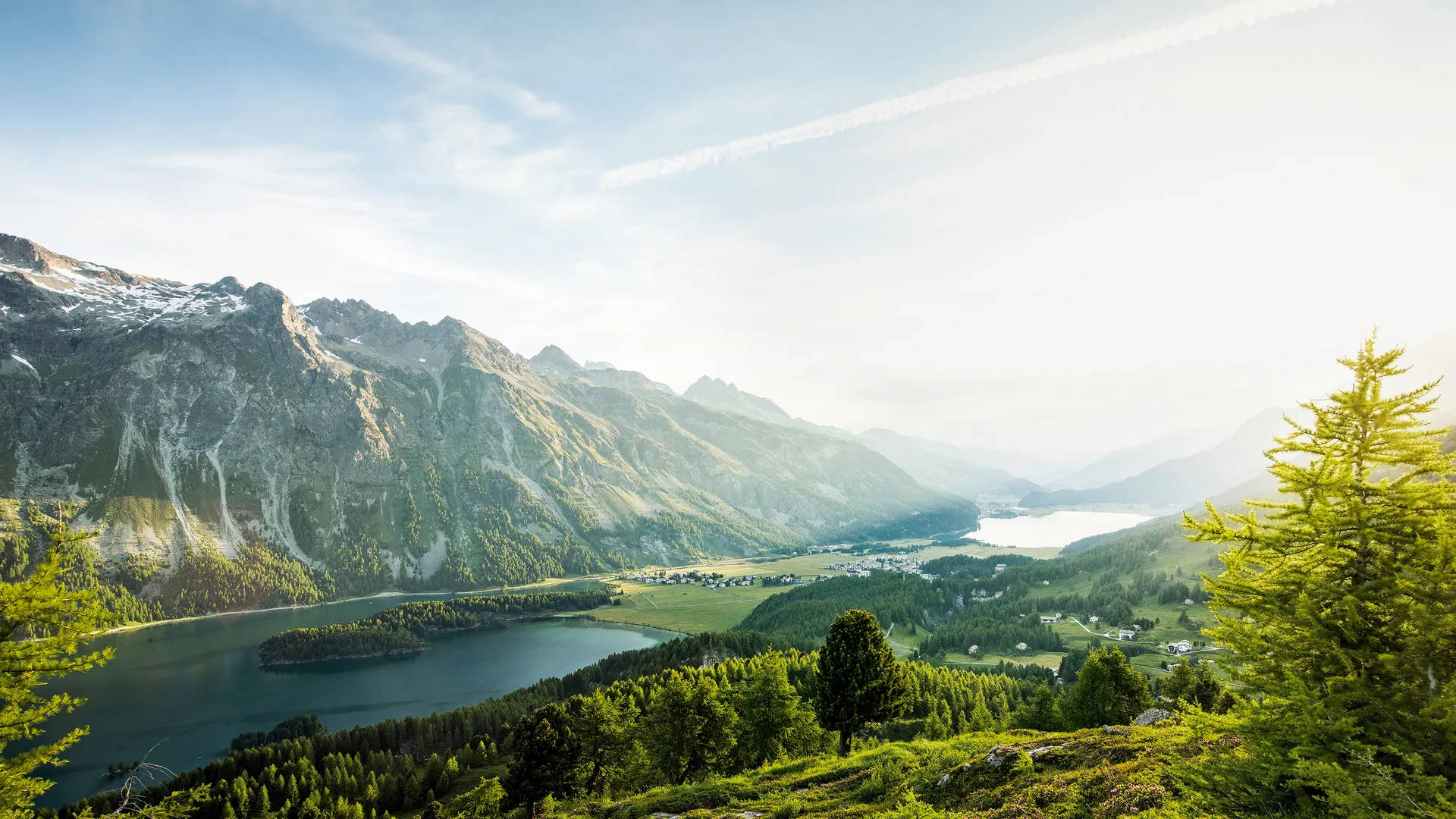 夏日瑞士阿爾卑斯山 壁紙 — 令人驚嘆的阿爾卑斯山景，寧靜的湖泊坐落在高聳的青山之間，明亮的藍天中飄著縷縷白雲。