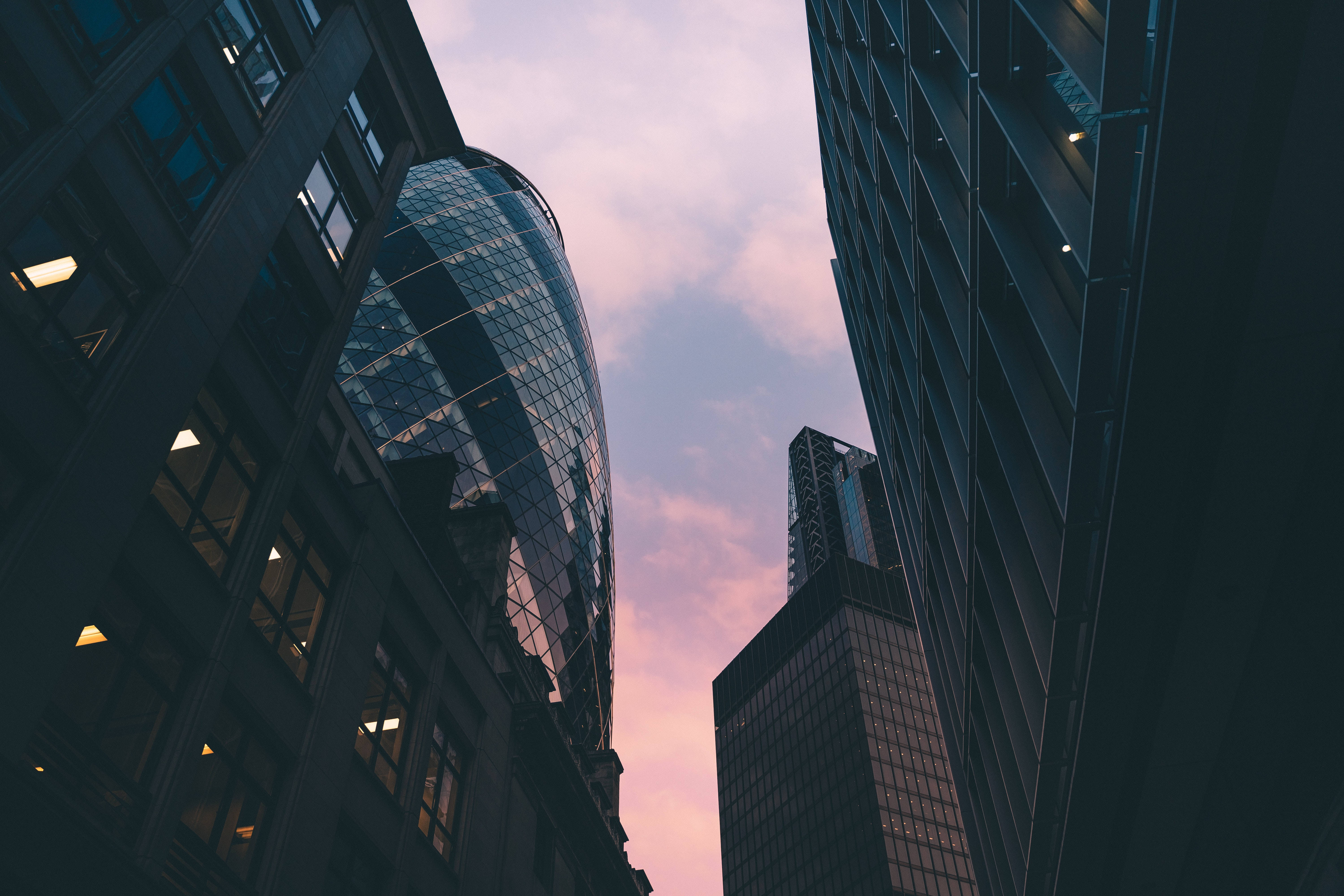 夕陽下的The Gherkin 壁紙 — 現代摩天大樓的低角度視角，粉紅色和紫色的暮色天空被玻璃幕牆框住，反射著逐漸消失的光線。