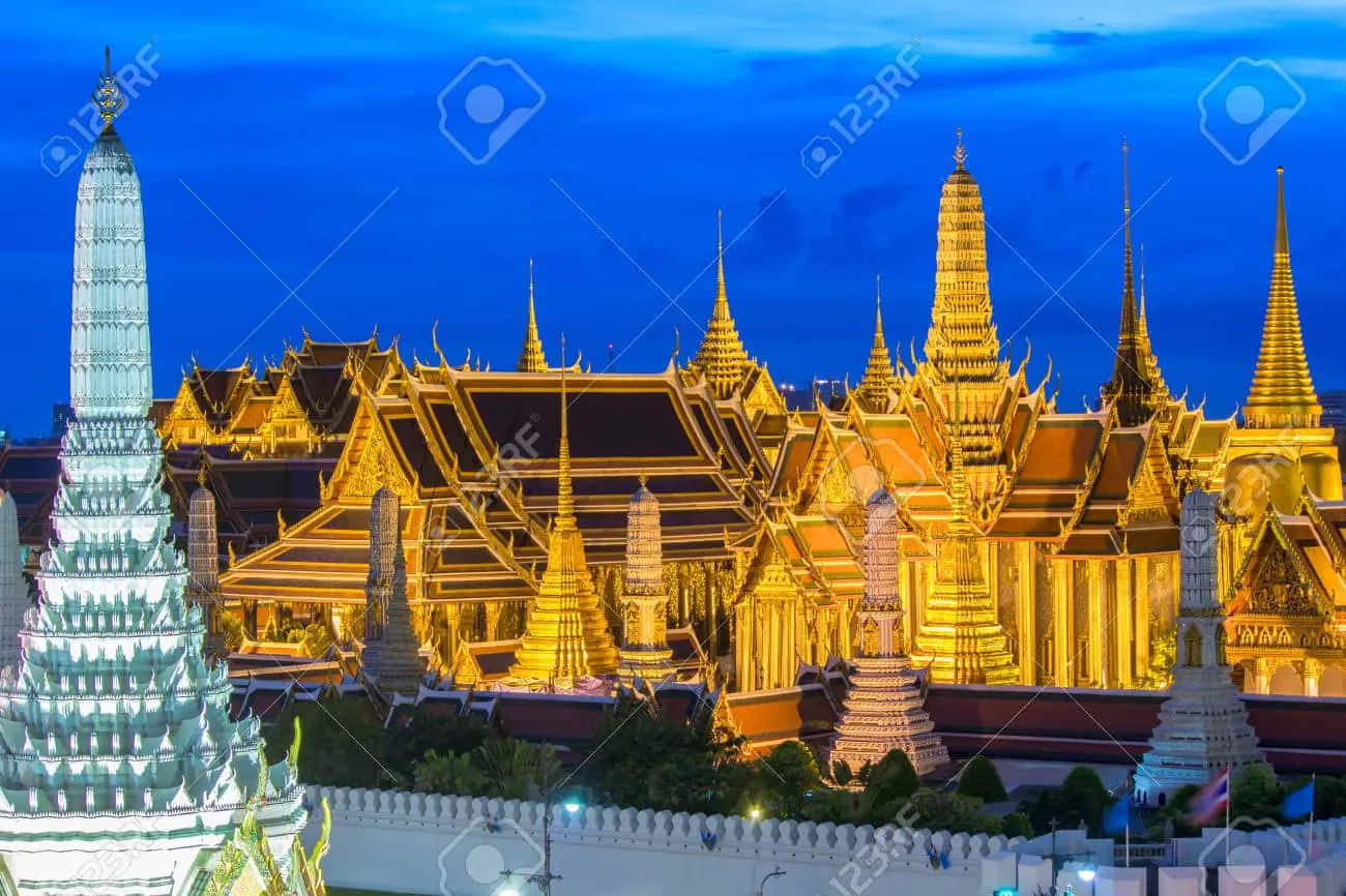 暮色中宏偉的燈光寺廟建築群，金色尖頂和藍色天空。