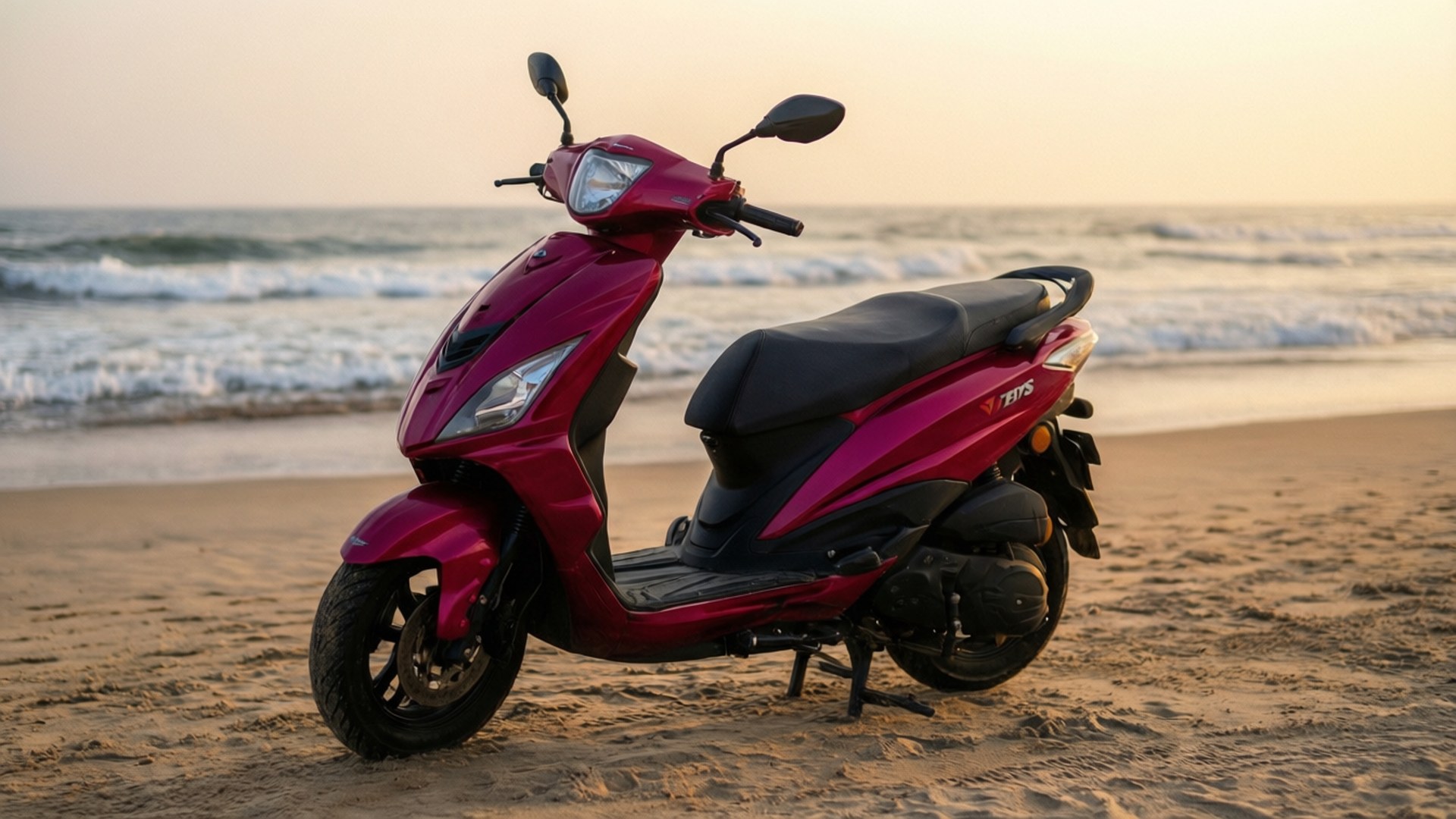 夕陽下的紅色Scooty 壁紙 — 一架亮面洋紅色電單車停泊在沙灘上，金色時刻海浪翻滾。