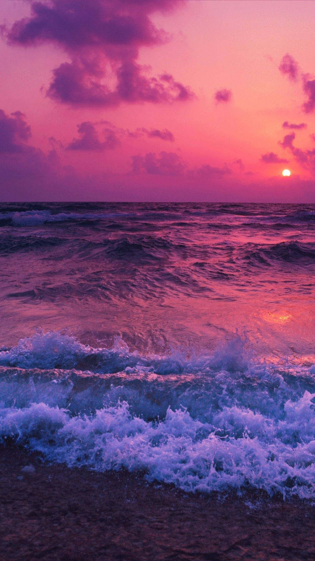 Aesthetic Sunset 桌布 壁紙 — 夕陽以粉紅和紫色調為海洋塗上鮮豔色彩，海浪拍打著海岸。