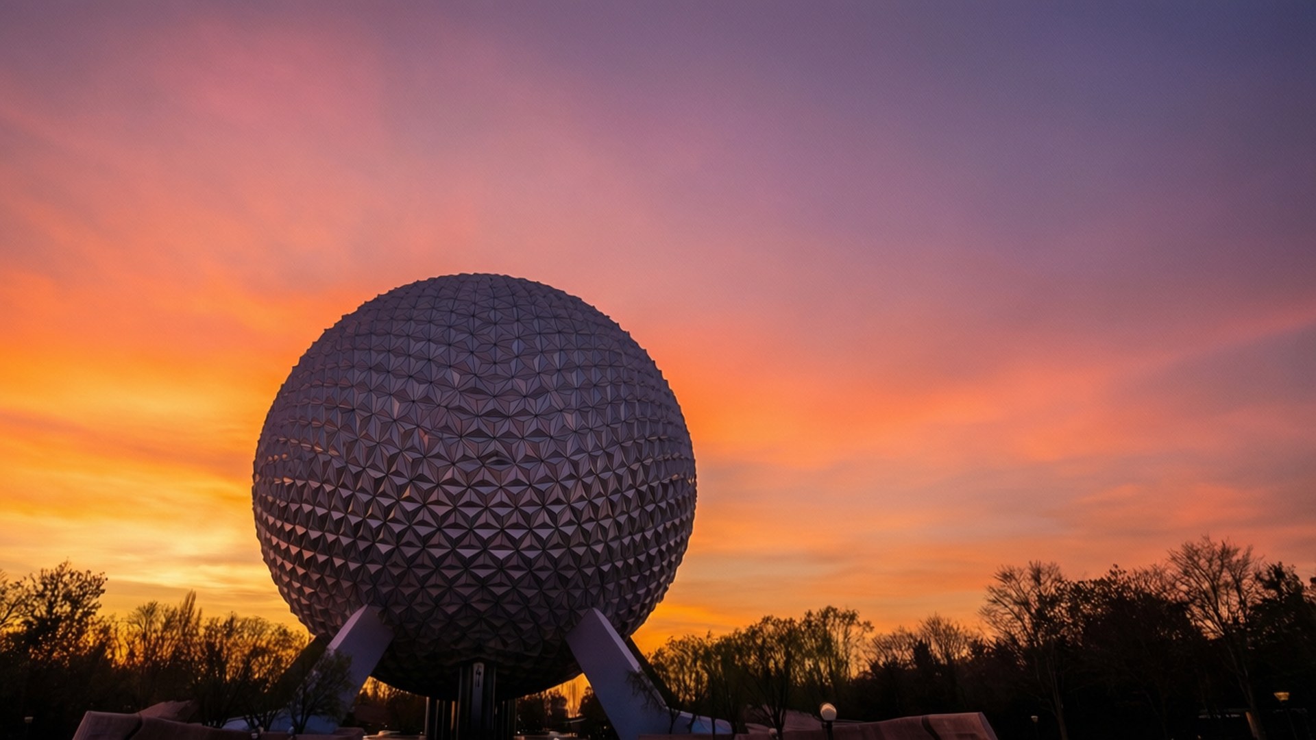 夕陽剪影 壁紙 — Spaceship Earth 的測地線球體在充滿活力的橙紫色日落天空下閃耀。