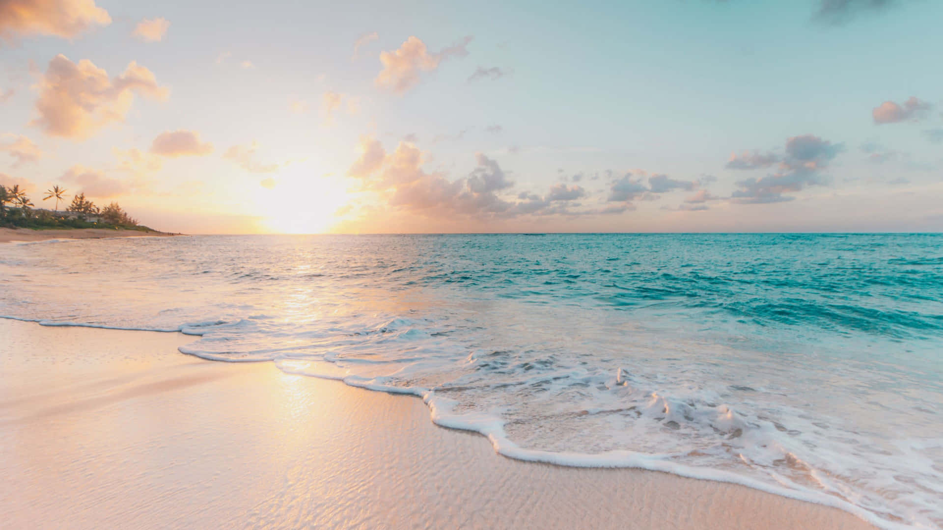 海灘日落 桌布 壁紙 — 夕陽將天空和海洋染成溫暖的金色和柔和的藍色，溫柔的海浪親吻著沙灘。
