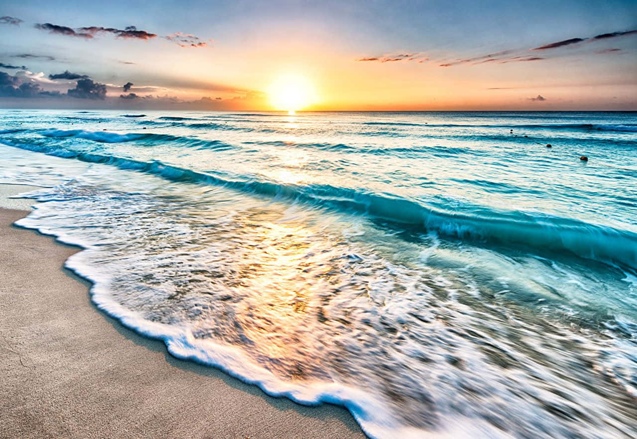 墨西哥 桌布 壁紙 — 夕陽將海洋染成金色，海浪在柔和的暮色天空下拍打著沙灘。