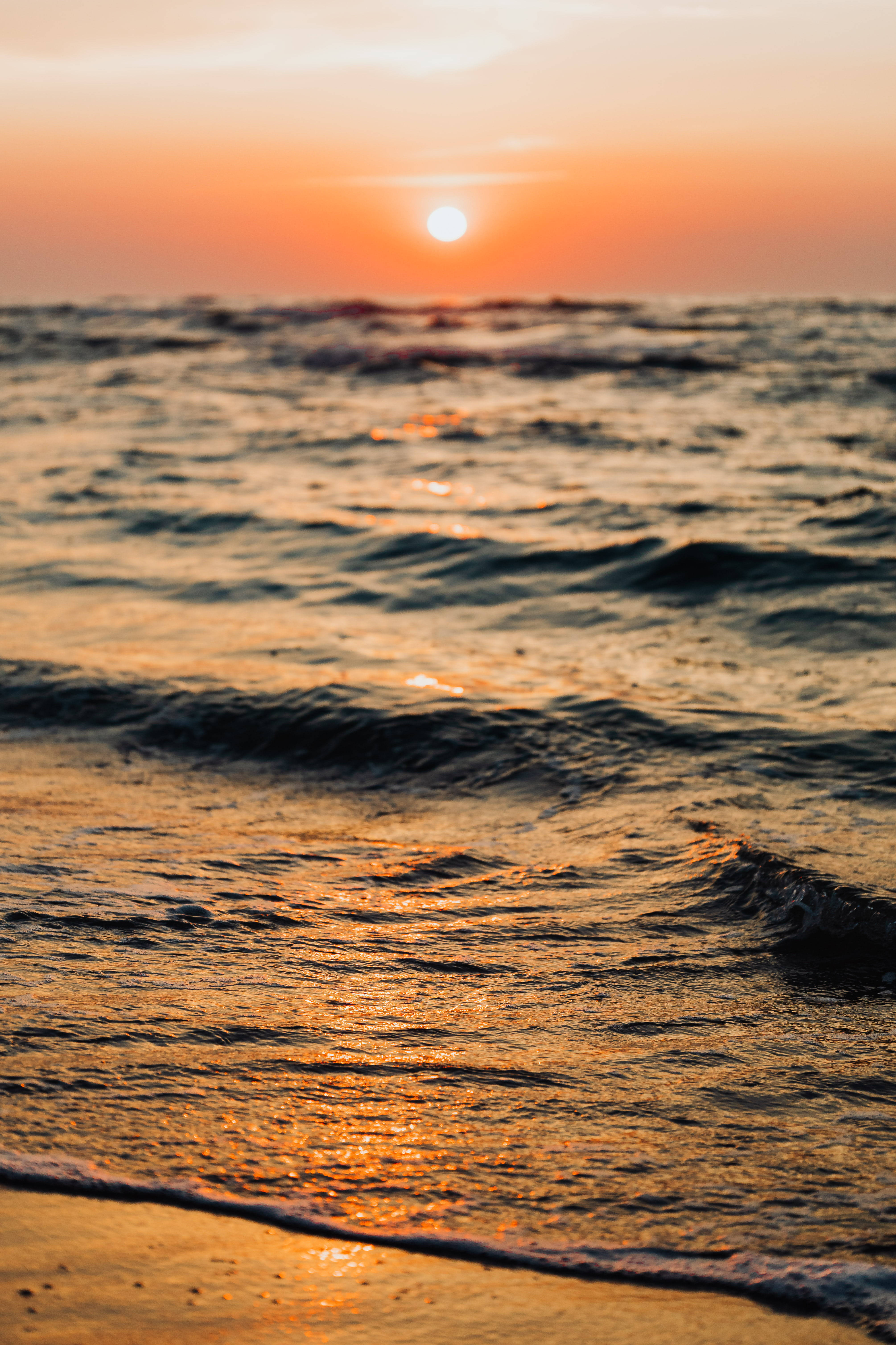 波浪 桌布 壁紙 — 夕陽將海浪染成溫暖的橙色和金色，輕輕拍打著海岸。