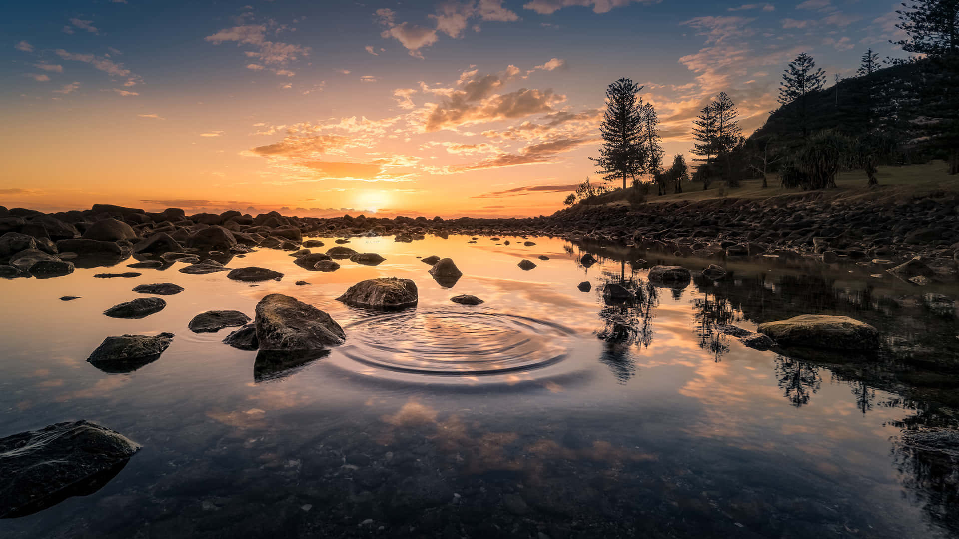 水面上的夕陽，漣漪和岩石海岸