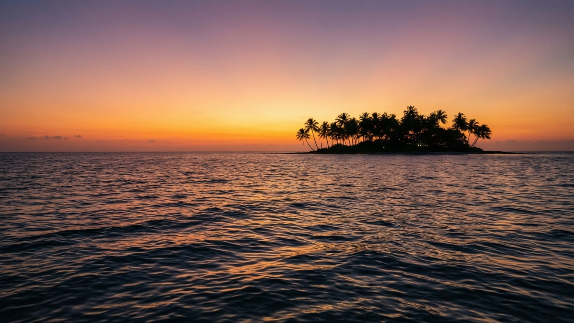 夕陽海景寧靜 壁紙 — 一個熱帶島嶼的剪影，棕櫚樹立在平靜的水面上，天空呈現鮮豔的橙色和紫色日落。