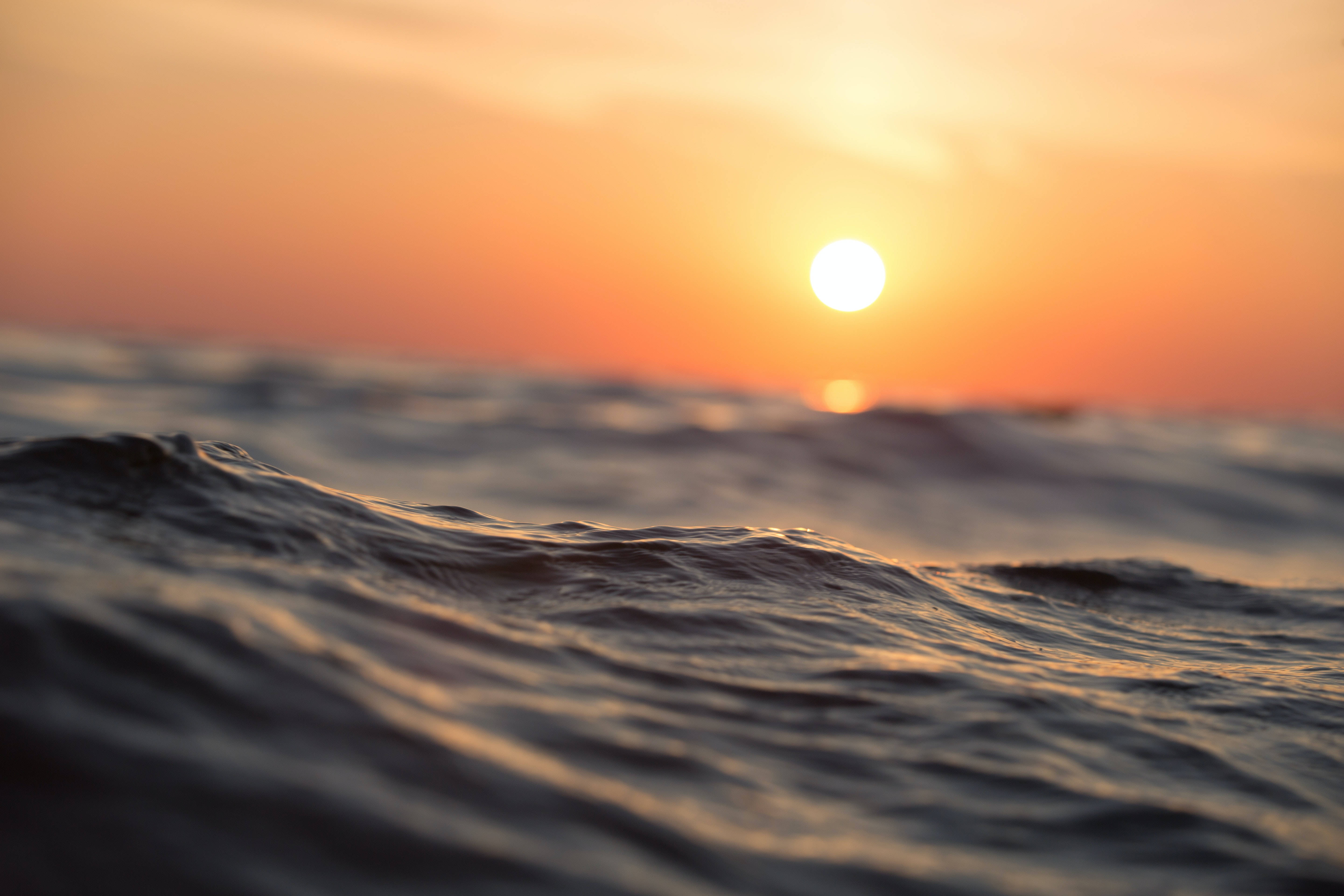 waves 桌布 壁紙 — 夕陽溫暖地照耀在紋理海洋波浪上，呈現寧靜的海岸場景。