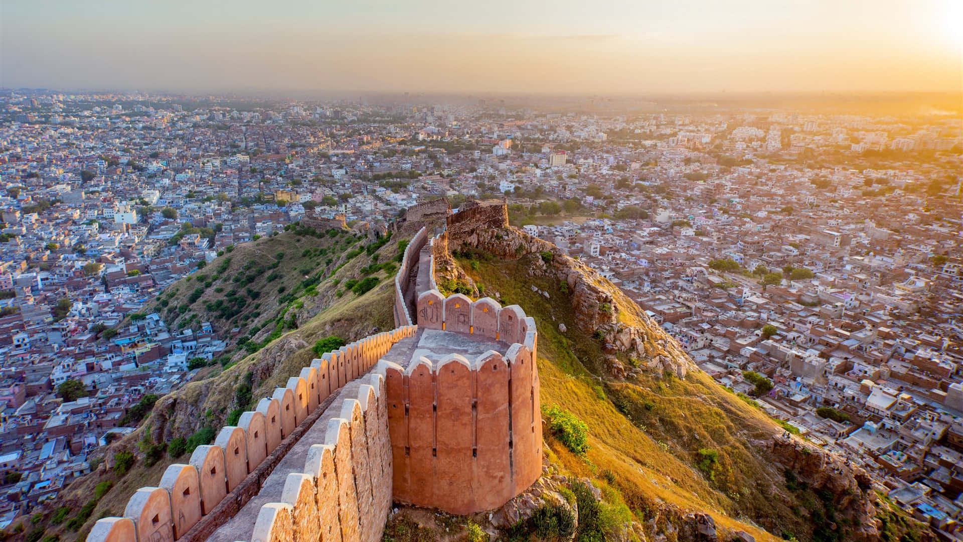 Rajasthan 桌布 壁紙 — 夕陽灑落在一座位於山頂的歷史堡壘上，俯瞰下方廣闊的城市景觀。