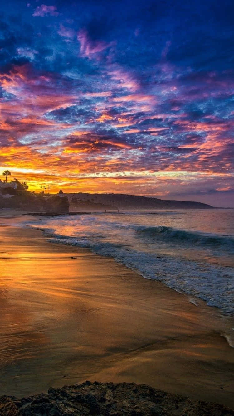 夕陽的燦爛光芒 壁紙 — 夕陽西下，絢麗的色彩將天空染成火熱的橙色和深紫色，映照在平靜的海灘和溫柔的海浪之上。