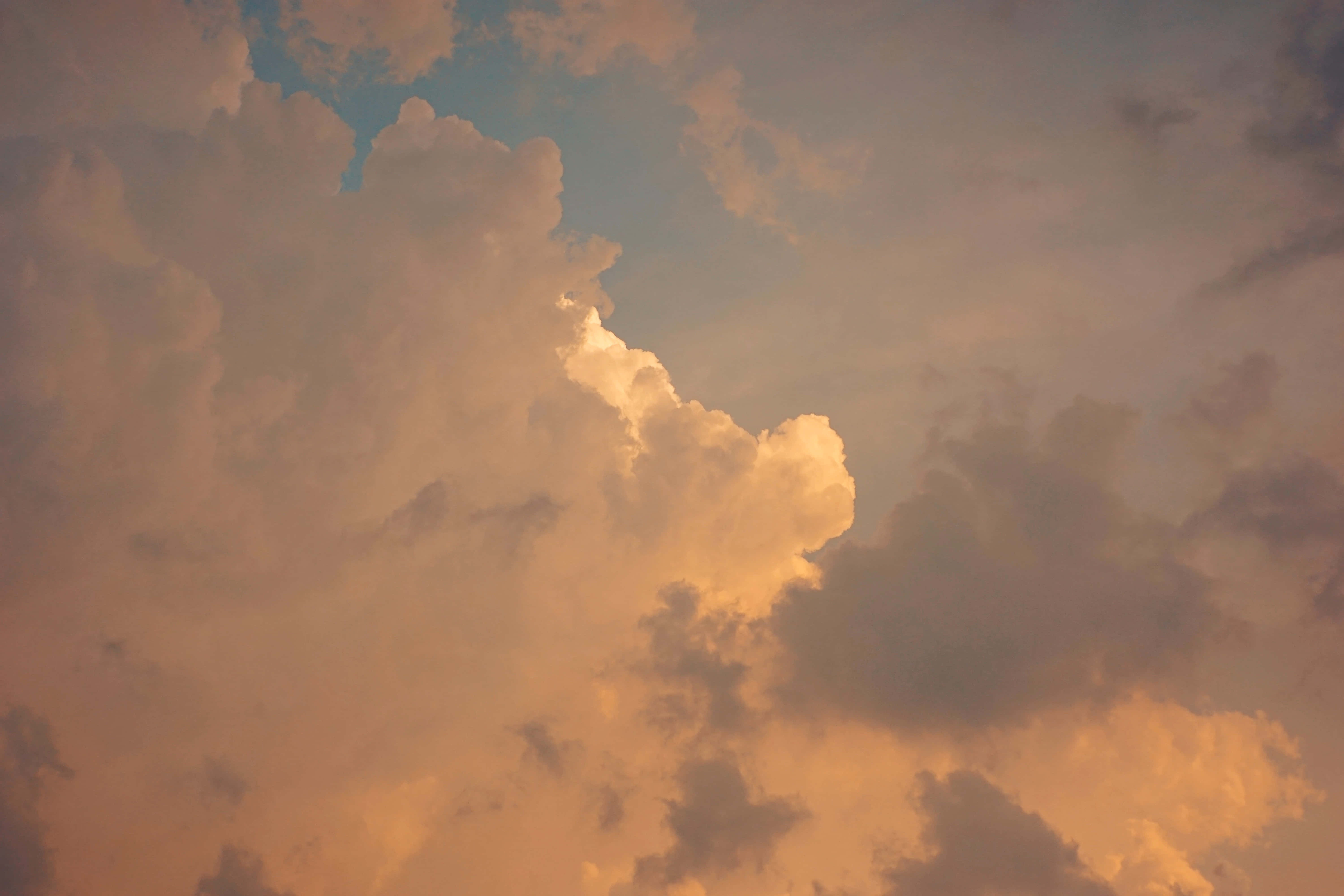 唯美雲朵動態 桌布 壁紙 — 夕陽穿透雲層時，豐厚的雲朵散發出溫暖的琥珀色和柔和的藍色光芒。