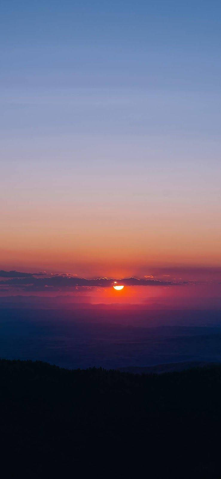 日落 桌布 壁紙 — 夕陽西下，天空被染成火橙色和深紫色，太陽沉沒在遠處山脊之下。