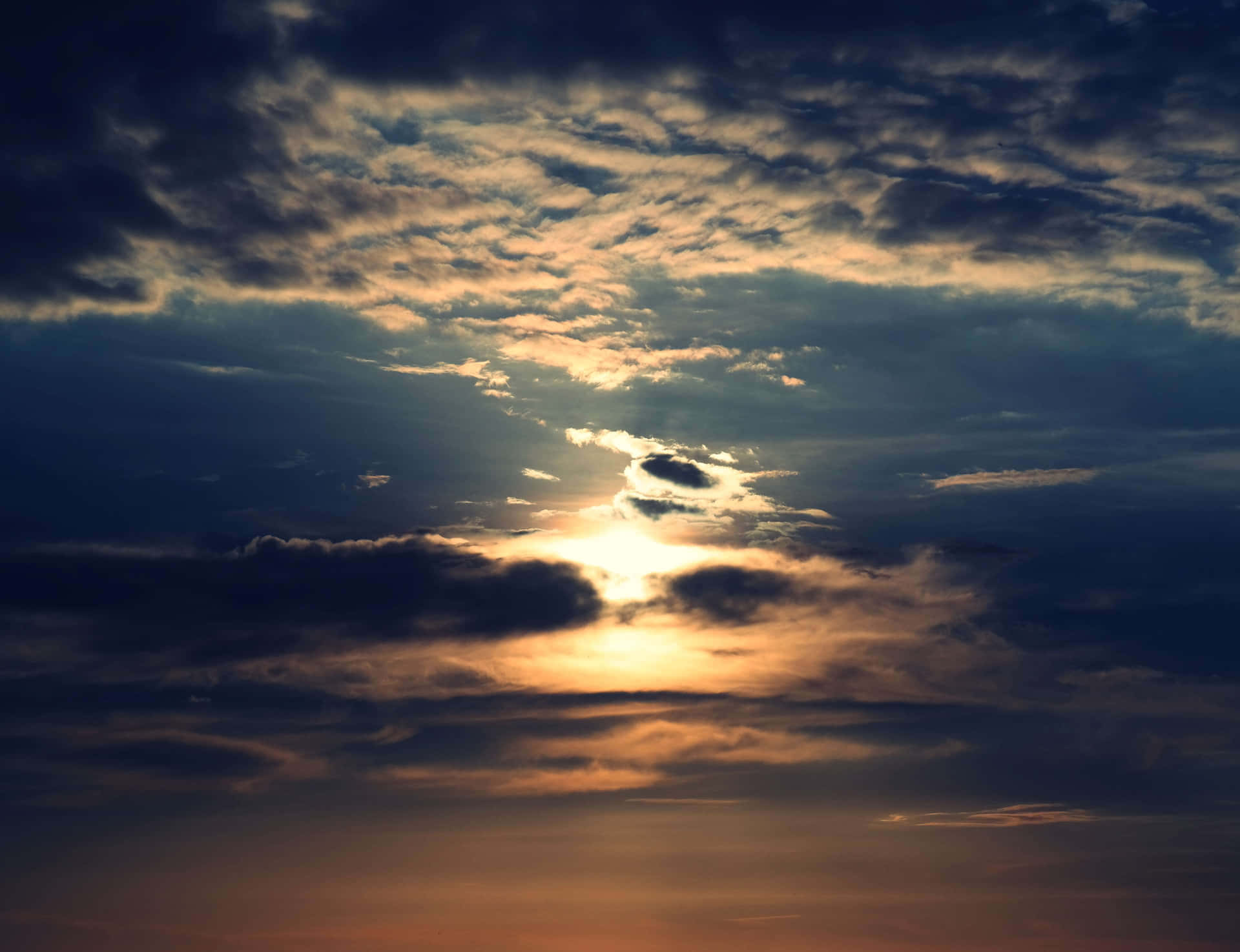 日落時陽光穿透烏雲，投射出金色光芒。
