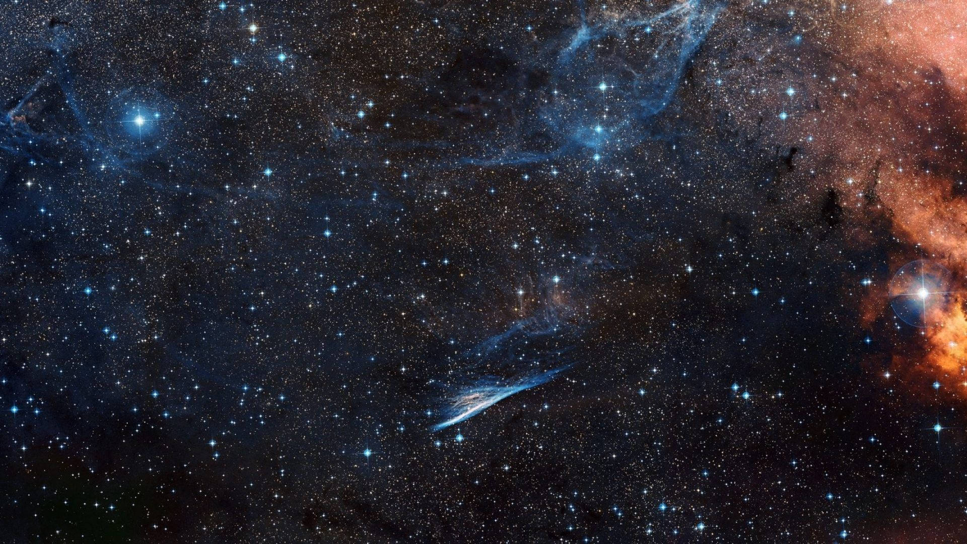 廣闊的星場，深空中發光的藍色和橙色星雲。