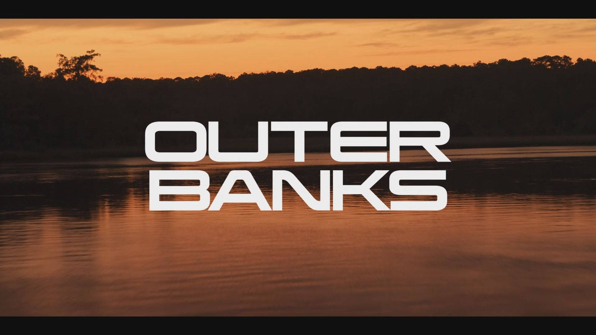水面上嘅日落，帶有「Outer Banks」文字疊加。