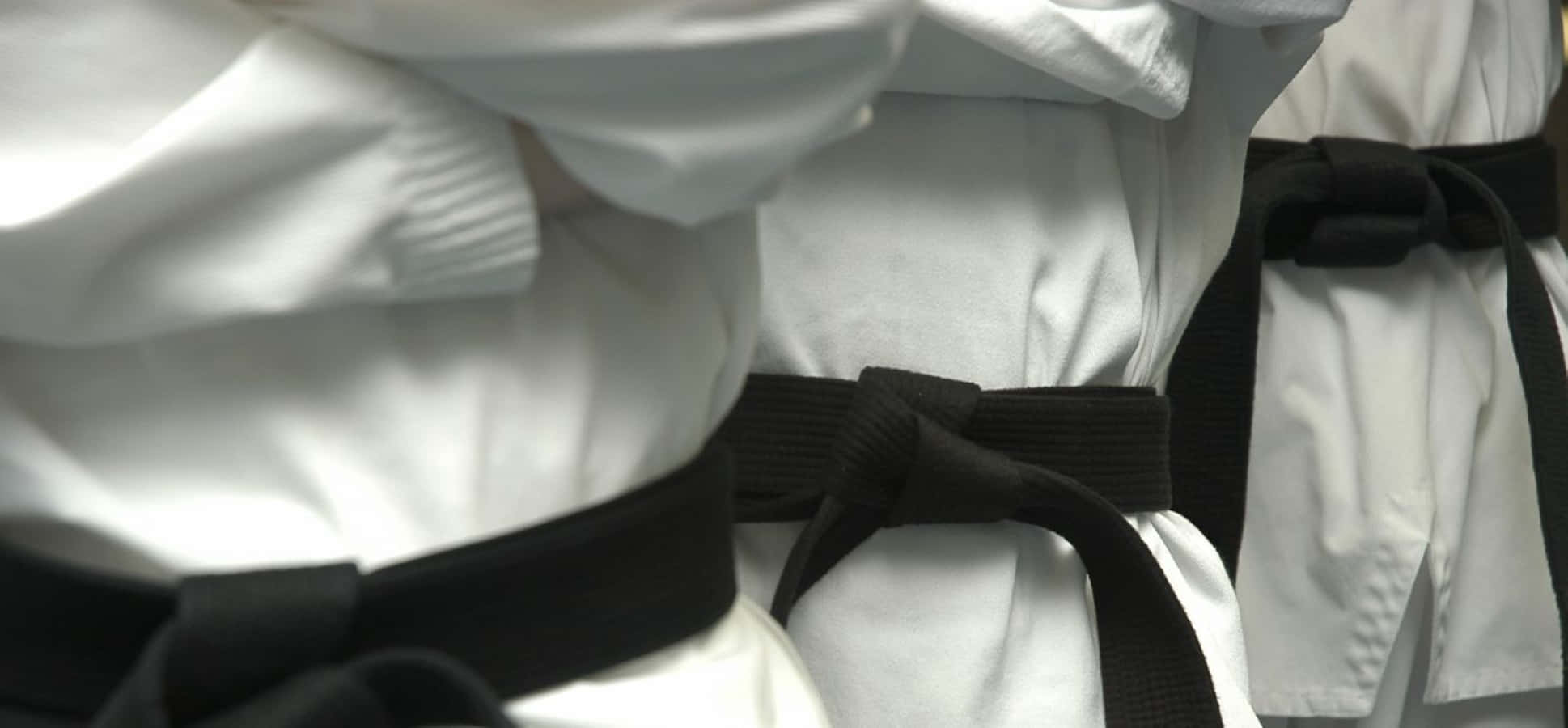 Martial Arts Uniform 桌布 壁紙 — 多件白色武術制服的特寫，黑色腰帶整齊地打成蝴蝶結。