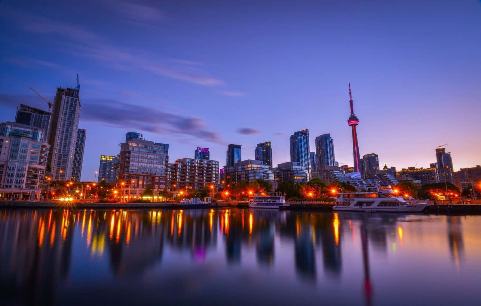 多倫多城市天際線 壁紙 — 令人驚嘆的暮色城市景觀，燈火通明的摩天大樓和CN塔倒映在平靜的水面上。