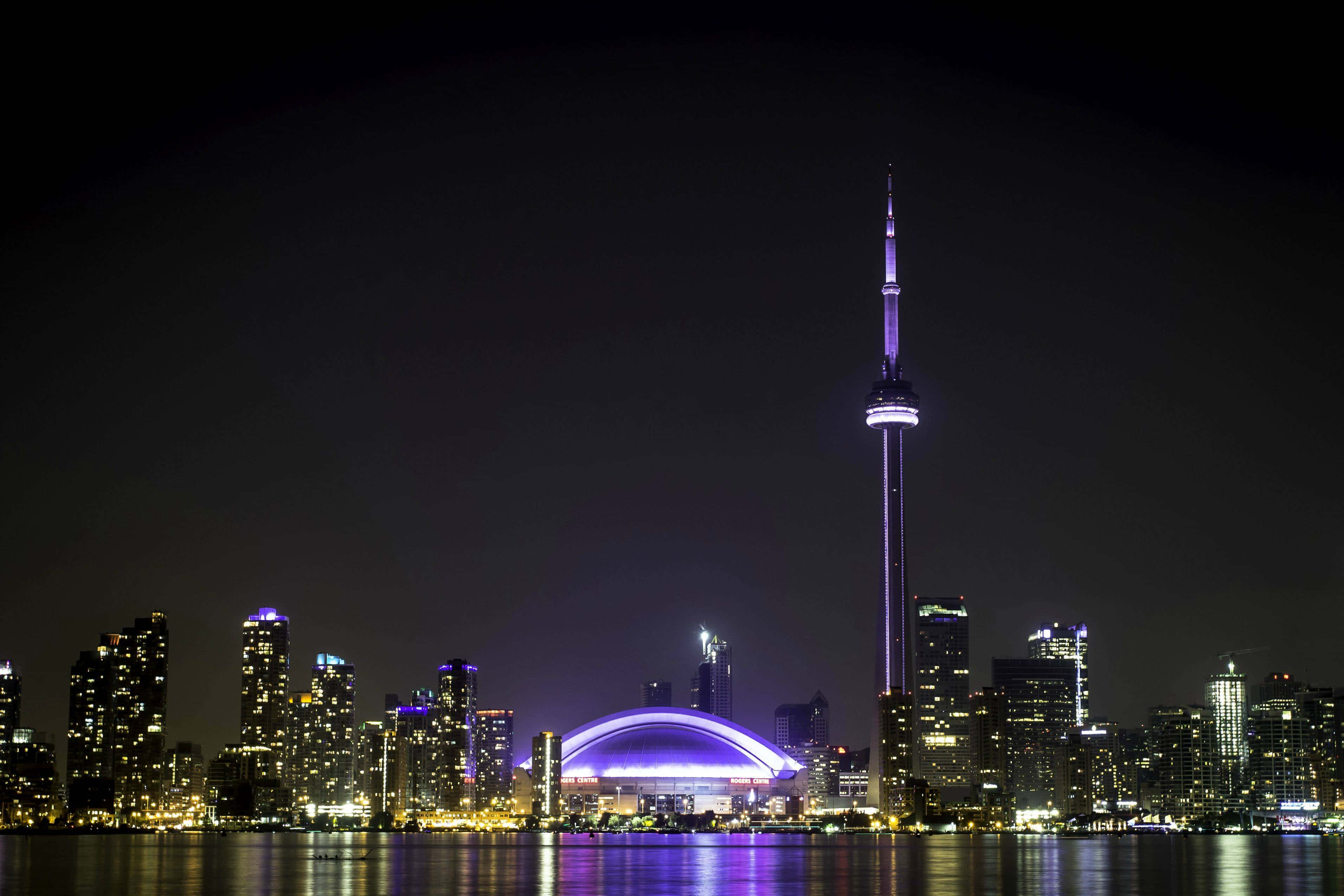 Toronto 桌布 壁紙 — 多倫多夜景，CN塔和羅渣士中心在水面上閃耀著紫色和金色。