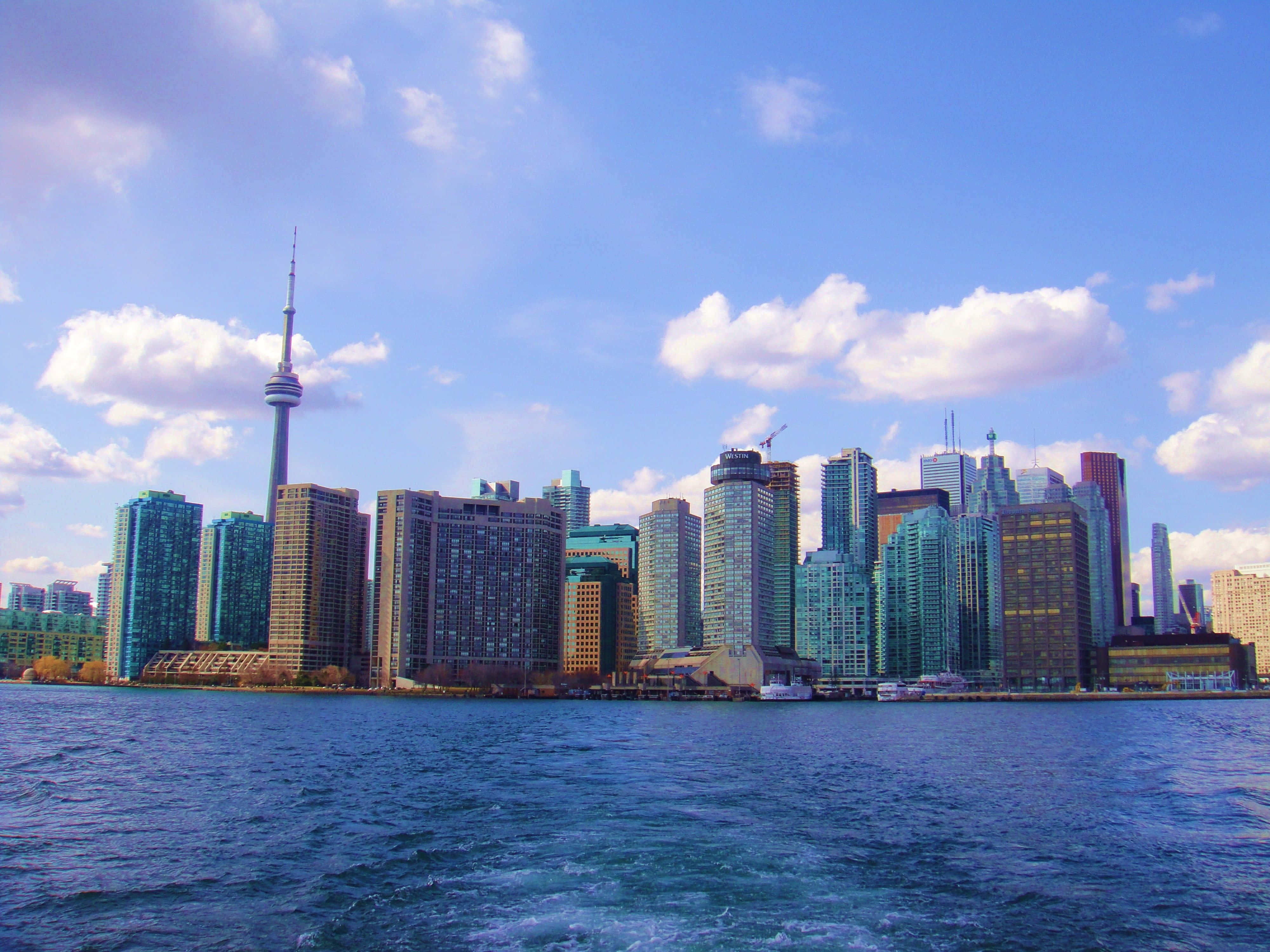Toronto 桌布 壁紙 — 多倫多天際線，CN塔和玻璃摩天大樓在部分多雲的天空下倒映在藍色水中。