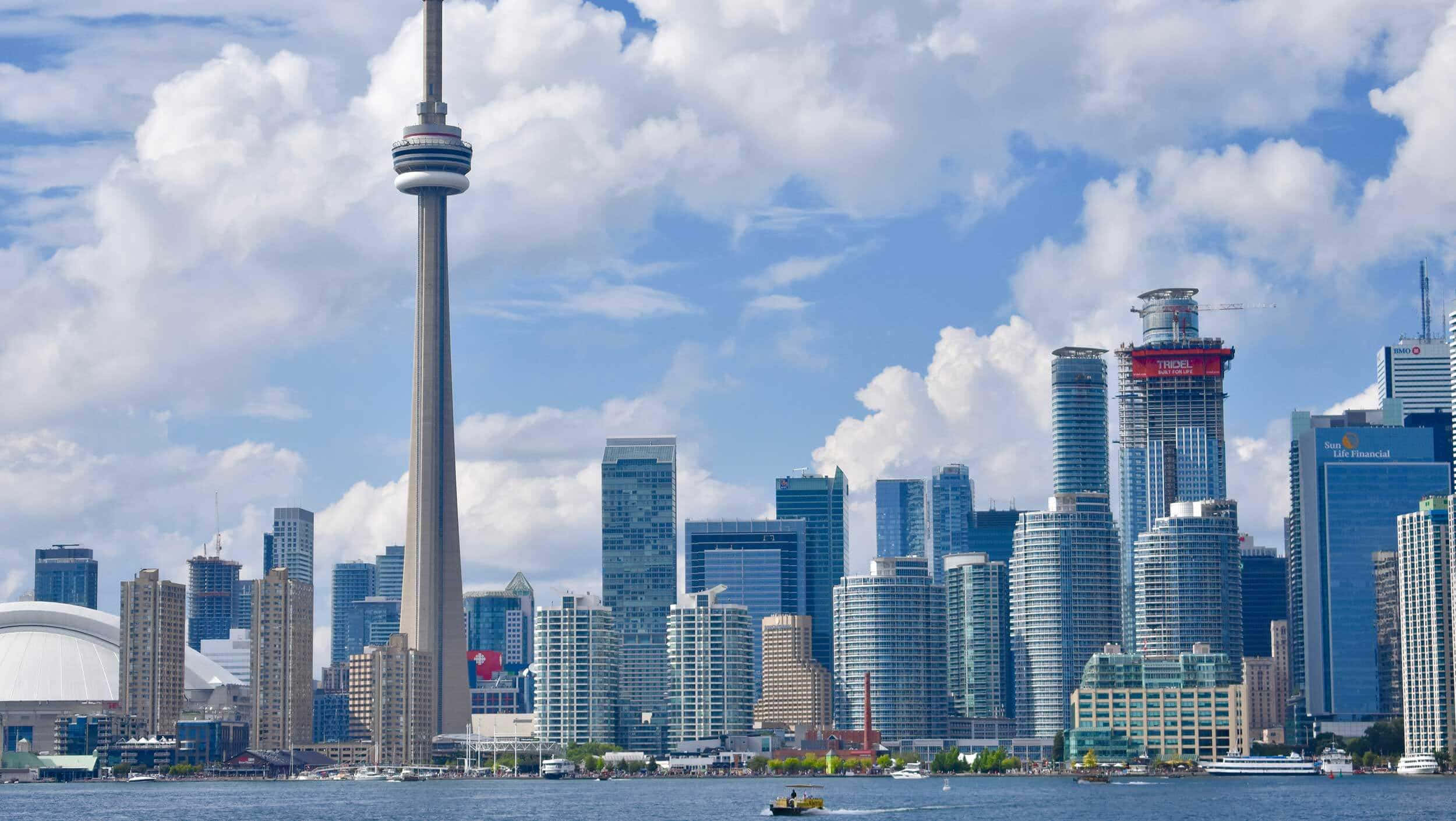 Canada 桌布 壁紙 — 多倫多天際線，CN塔和現代玻璃摩天大樓在明亮的藍天和蓬鬆的白雲下。