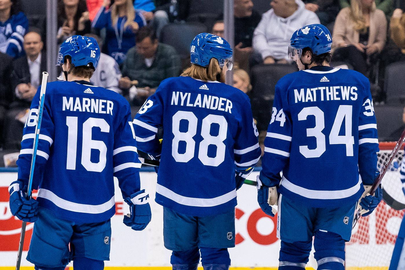 多倫多楓葉隊新星威廉·尼蘭德 壁紙 — 三名多倫多楓葉隊冰球球員身穿藍色球衣，在球迷背景下離開冰場。