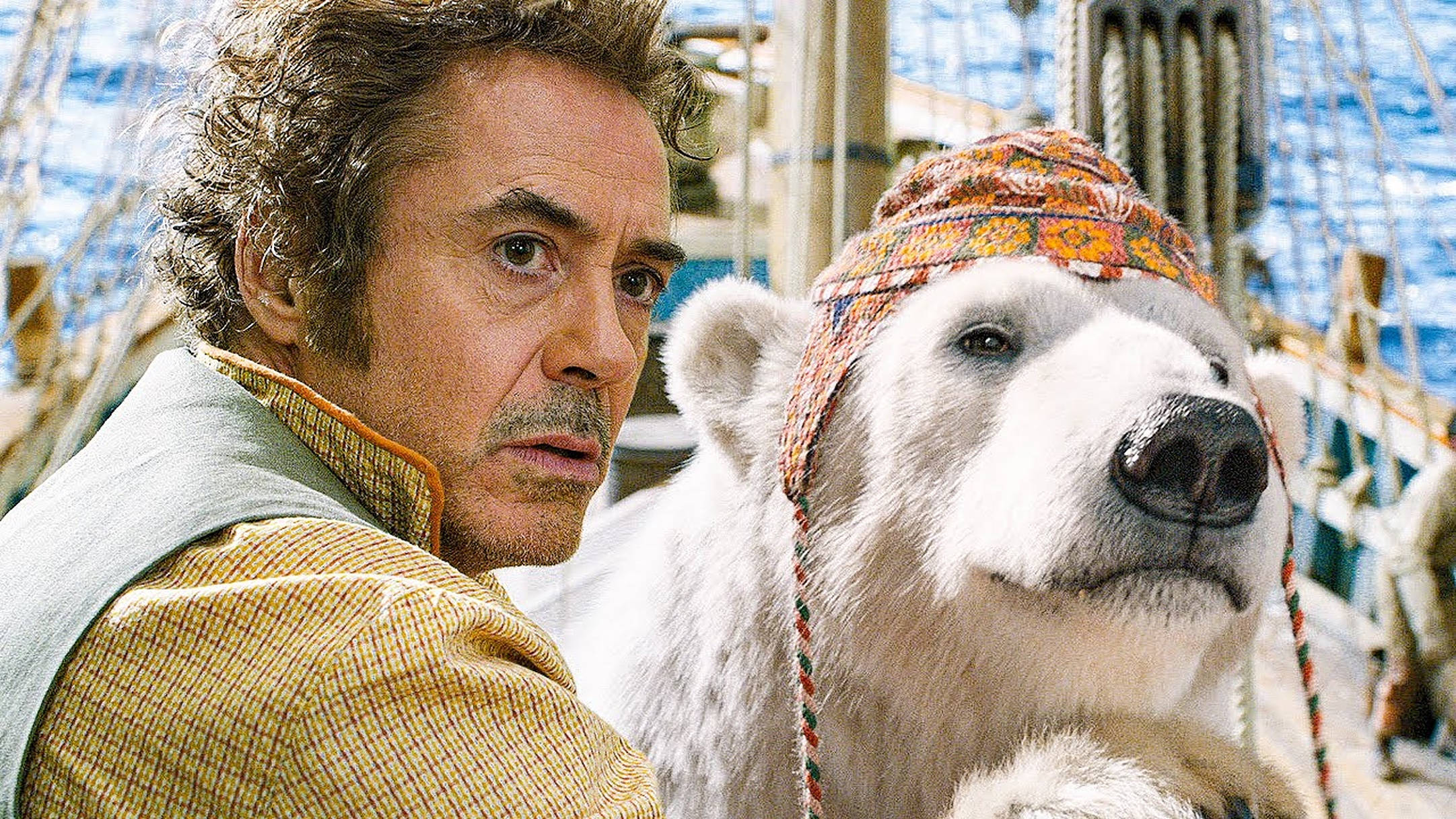 多力特與 Yoshi 熊 壁紙 — 演員羅拔·唐尼（Robert Downey Jr.）和一隻戴著色彩繽紛圖案帽子的北極熊並肩站在船甲板上。
