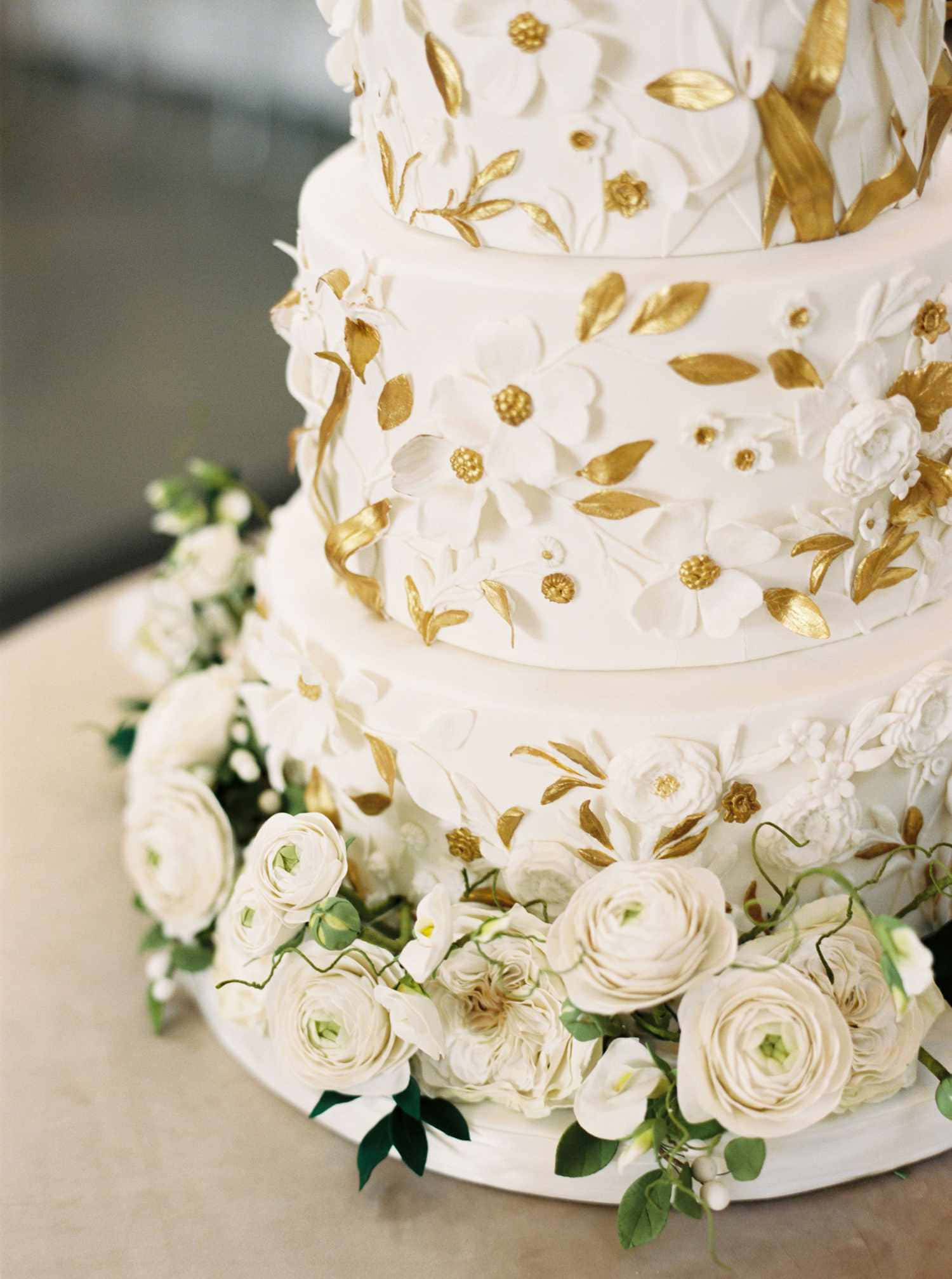 Cake Fondant 桌布 壁紙 — 多層白色結婚蛋糕，飾有金箔花和新鮮白玫瑰在底部。