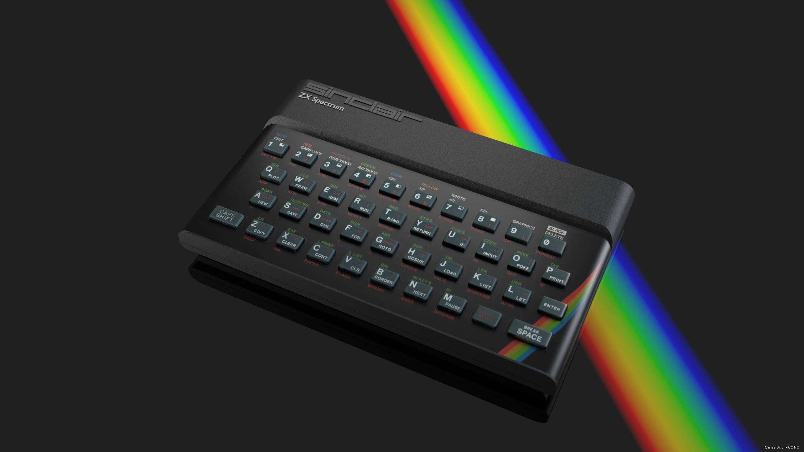 多彩光譜波浪 壁紙 — 一部黑色Sinclair ZX Spectrum電腦傾斜放置在深色背景上，一道鮮豔的彩虹棱鏡光束斜向穿過畫面。