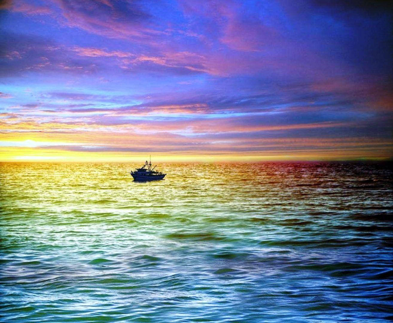 在戲劇性的日落中，一艘小船漂浮在色彩繽紛的海水上。