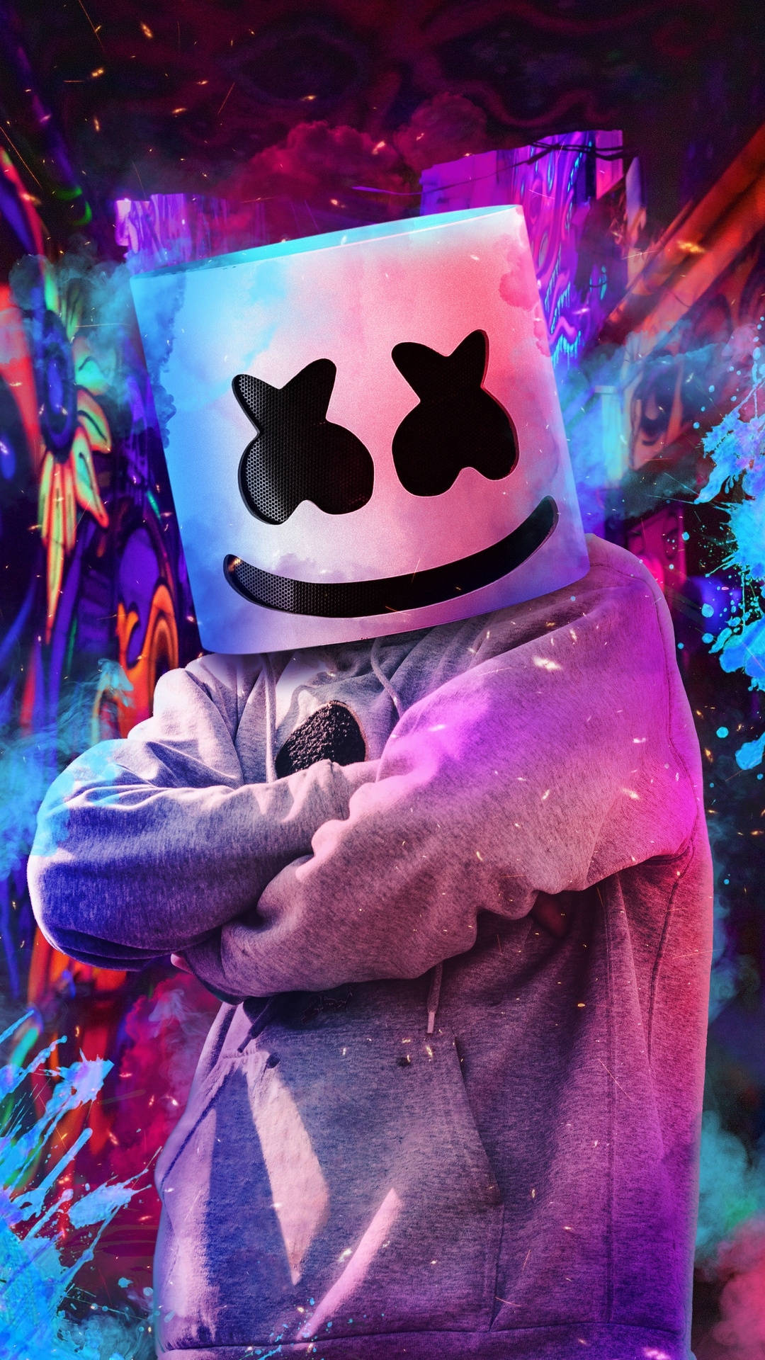 DJ Marshmello 戴著發光頭盔，雙臂交叉，站在色彩繽紛的塗鴉牆前。