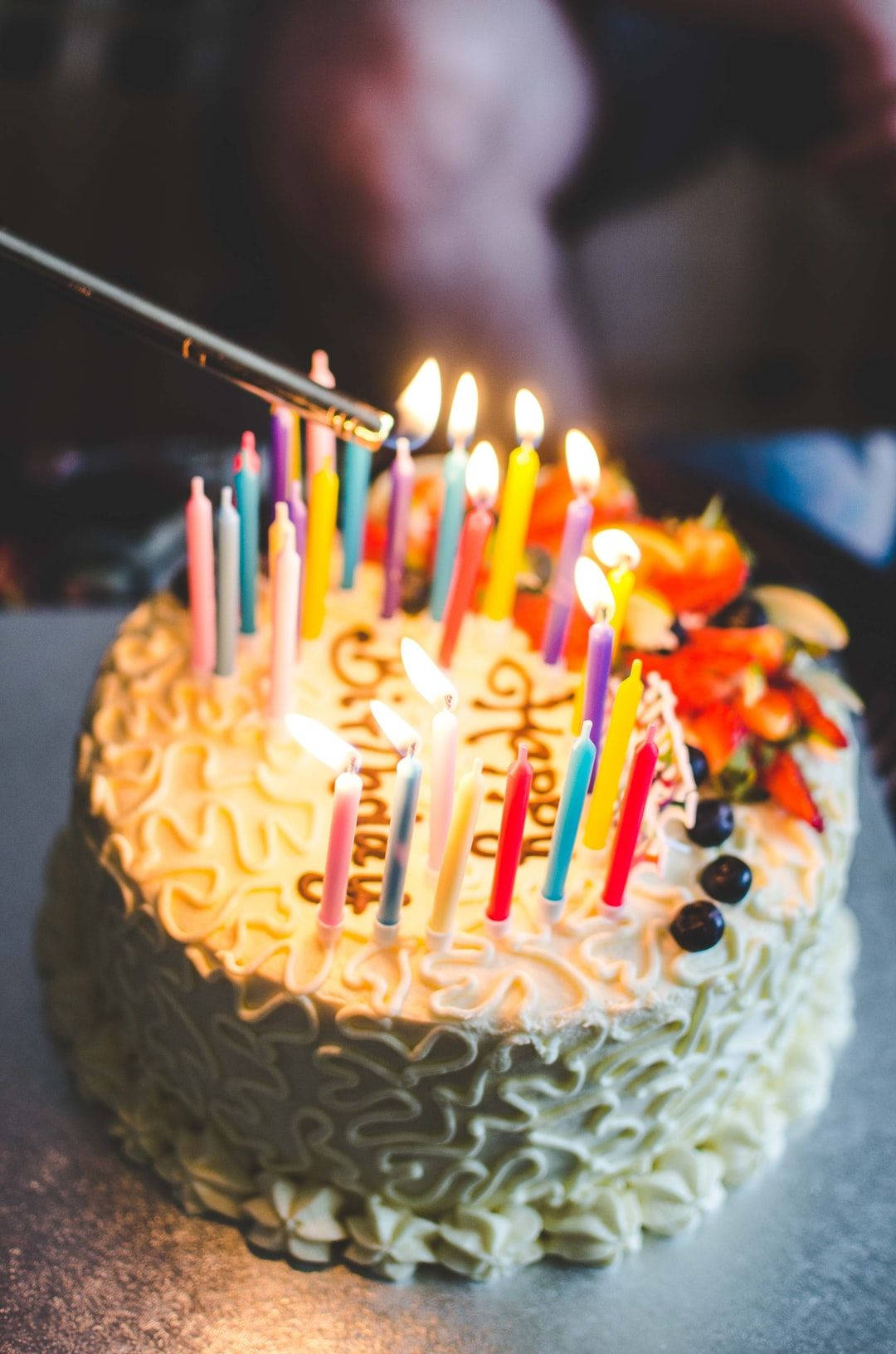 多支蠟燭生日蛋糕 壁紙 — 生日蛋糕的特寫，上面有燃燒的彩色蠟燭和新鮮水果配料。