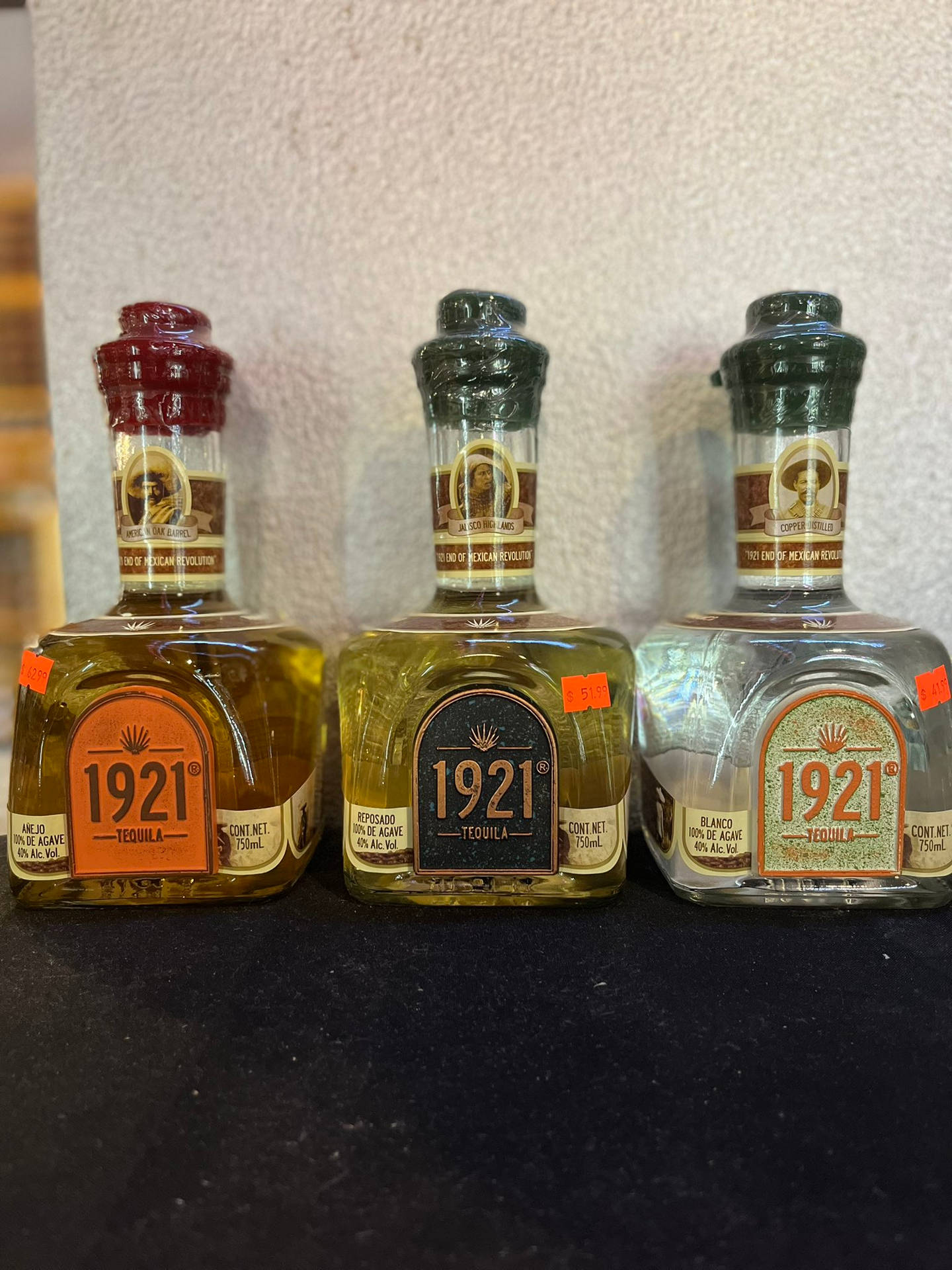 三瓶1921年龍舌蘭酒展示在深色表面上。