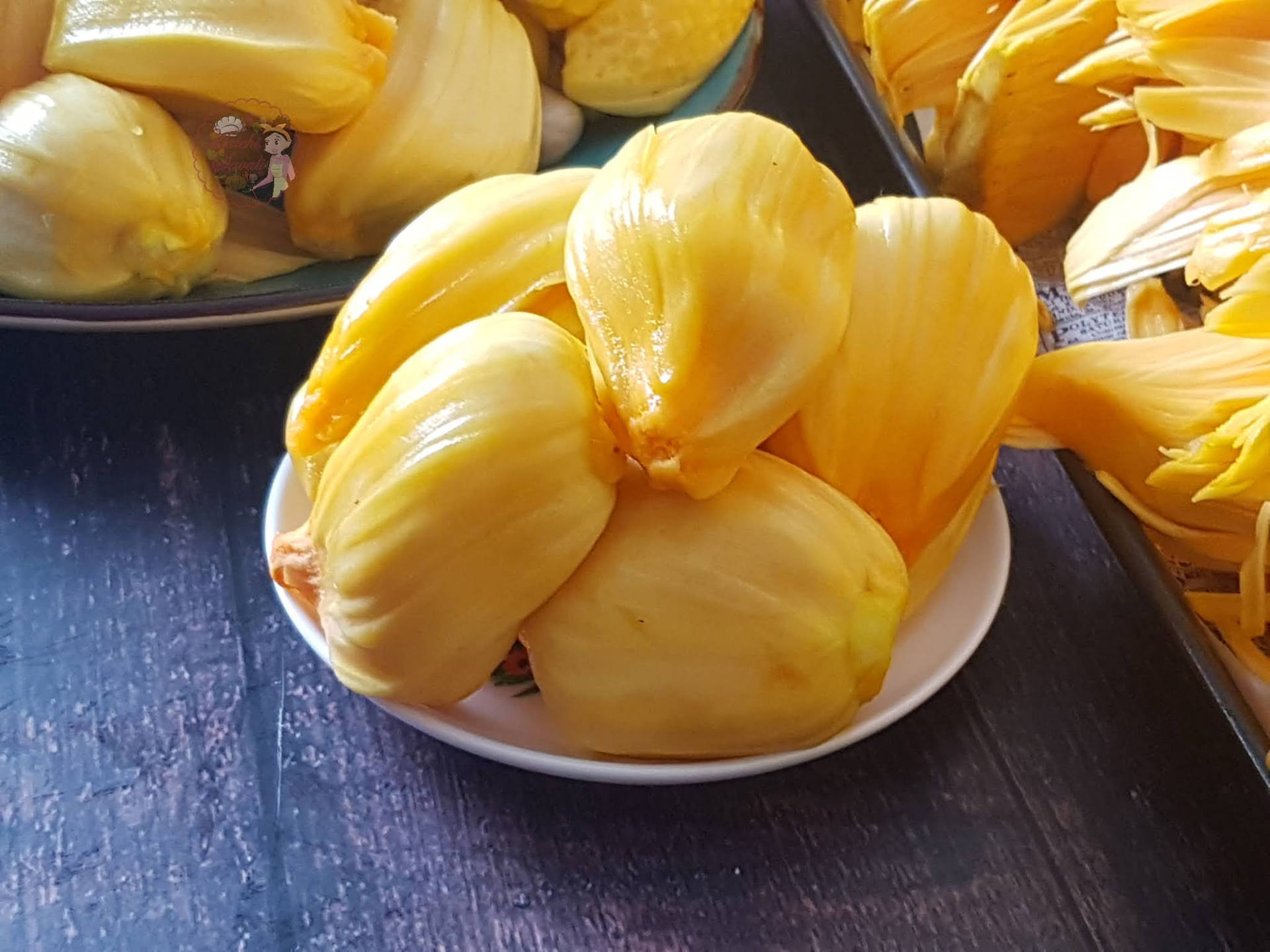 新鮮菠蘿蜜塊放在深色木桌上的白色碟子上。