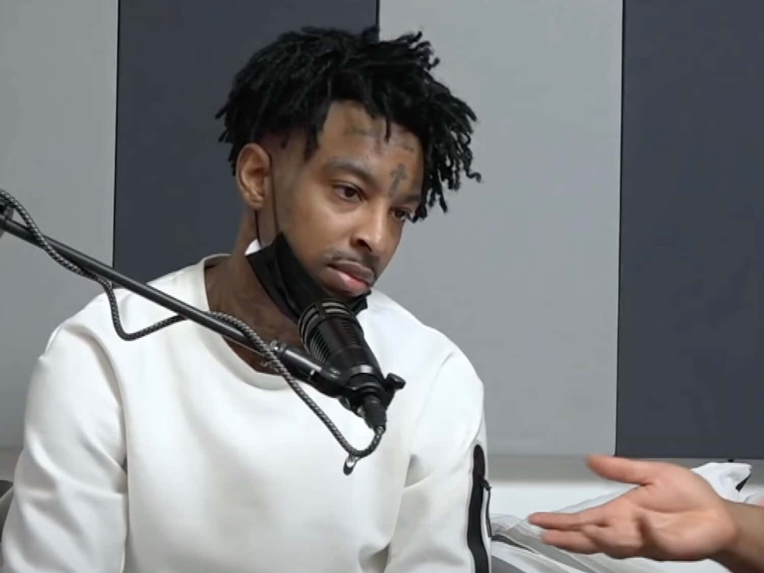 多白金、格萊美提名藝人 21 Savage 壁紙 — 一名留著辮子頭、臉上有紋身的男子，身穿白色衛衣，坐在錄音室裡對著麥克風說話。