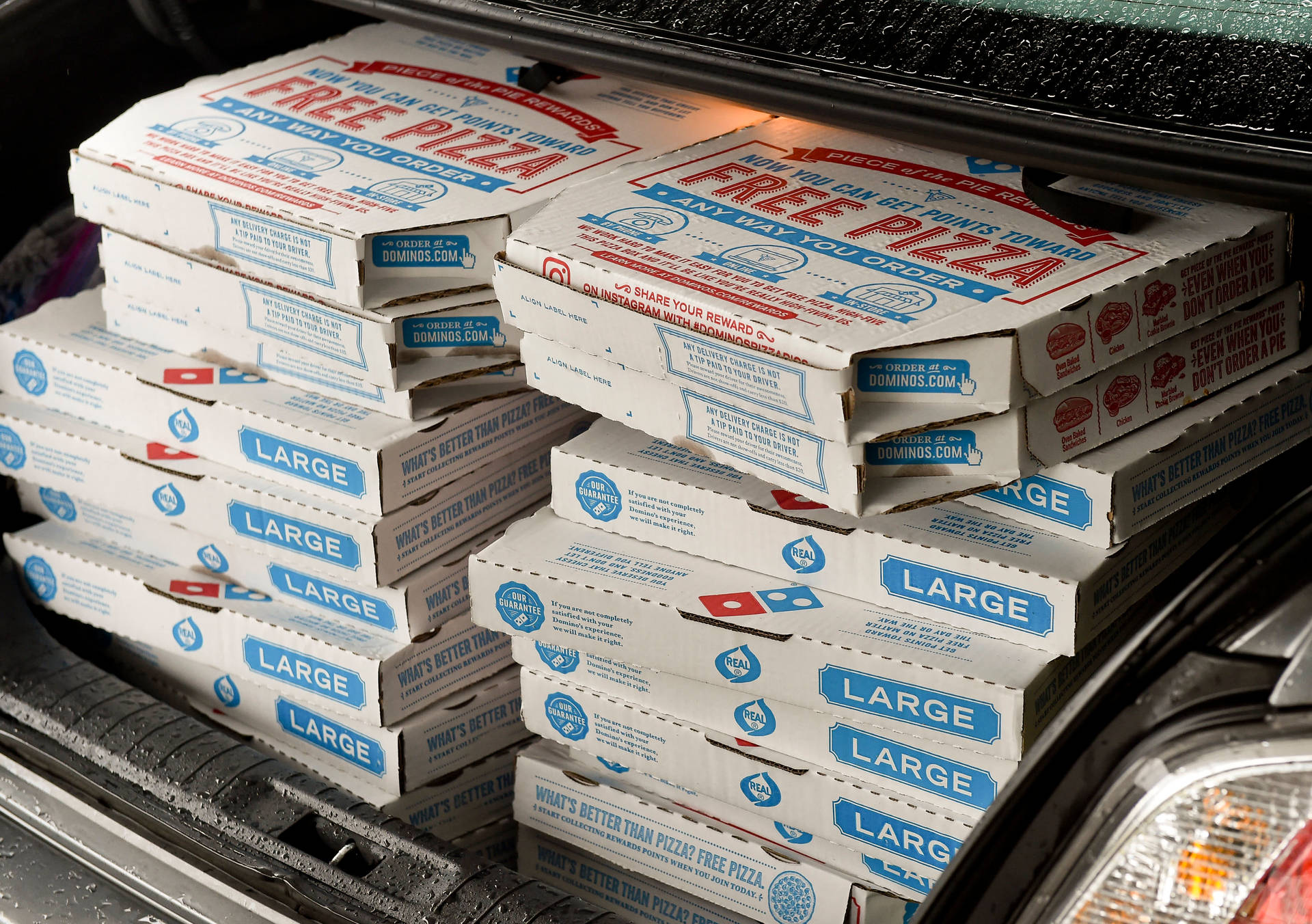 Domino's薄餅盒堆疊在汽車尾箱，準備送貨。